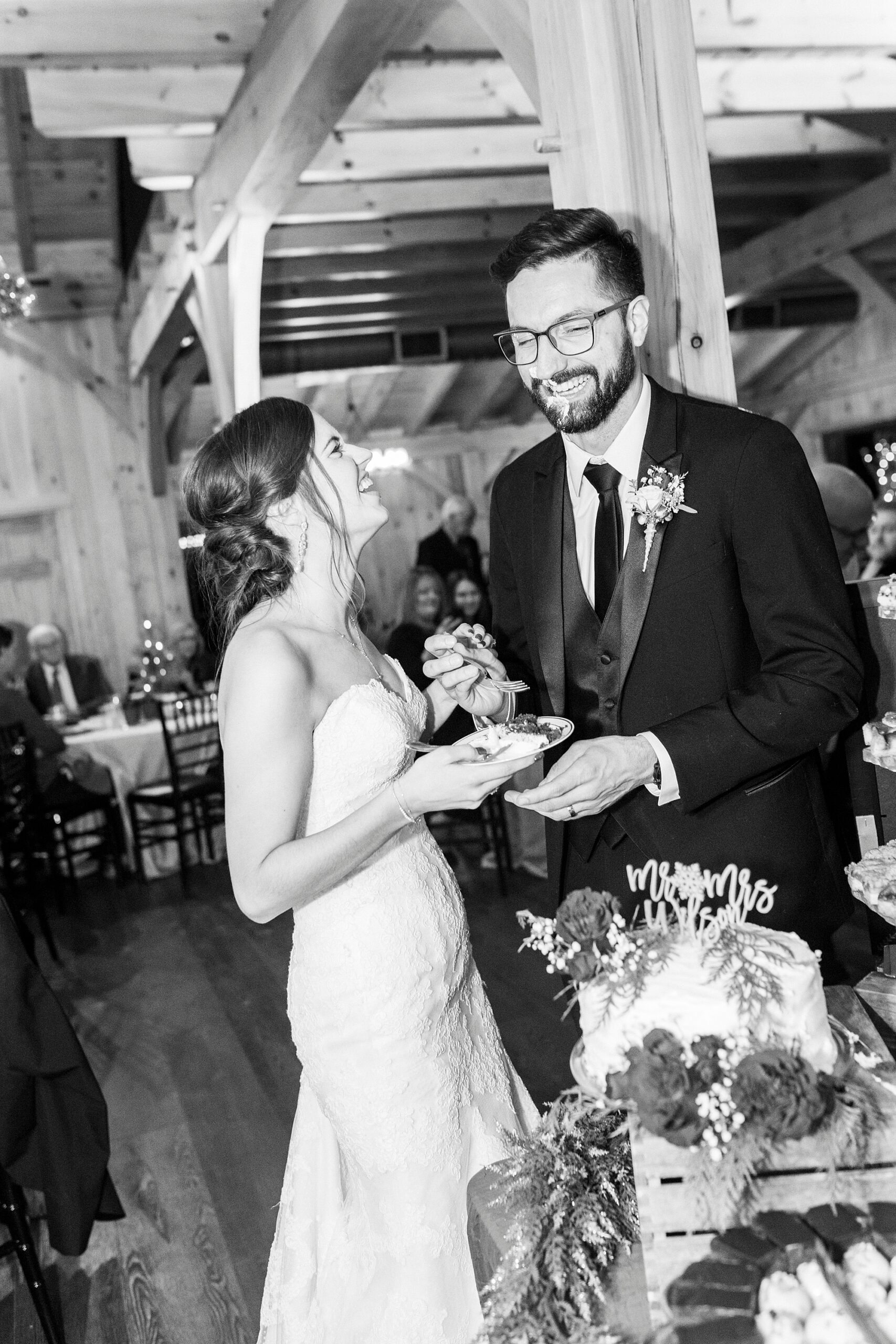 newlyweds laugh after shoving cake in each other's faces during reception 