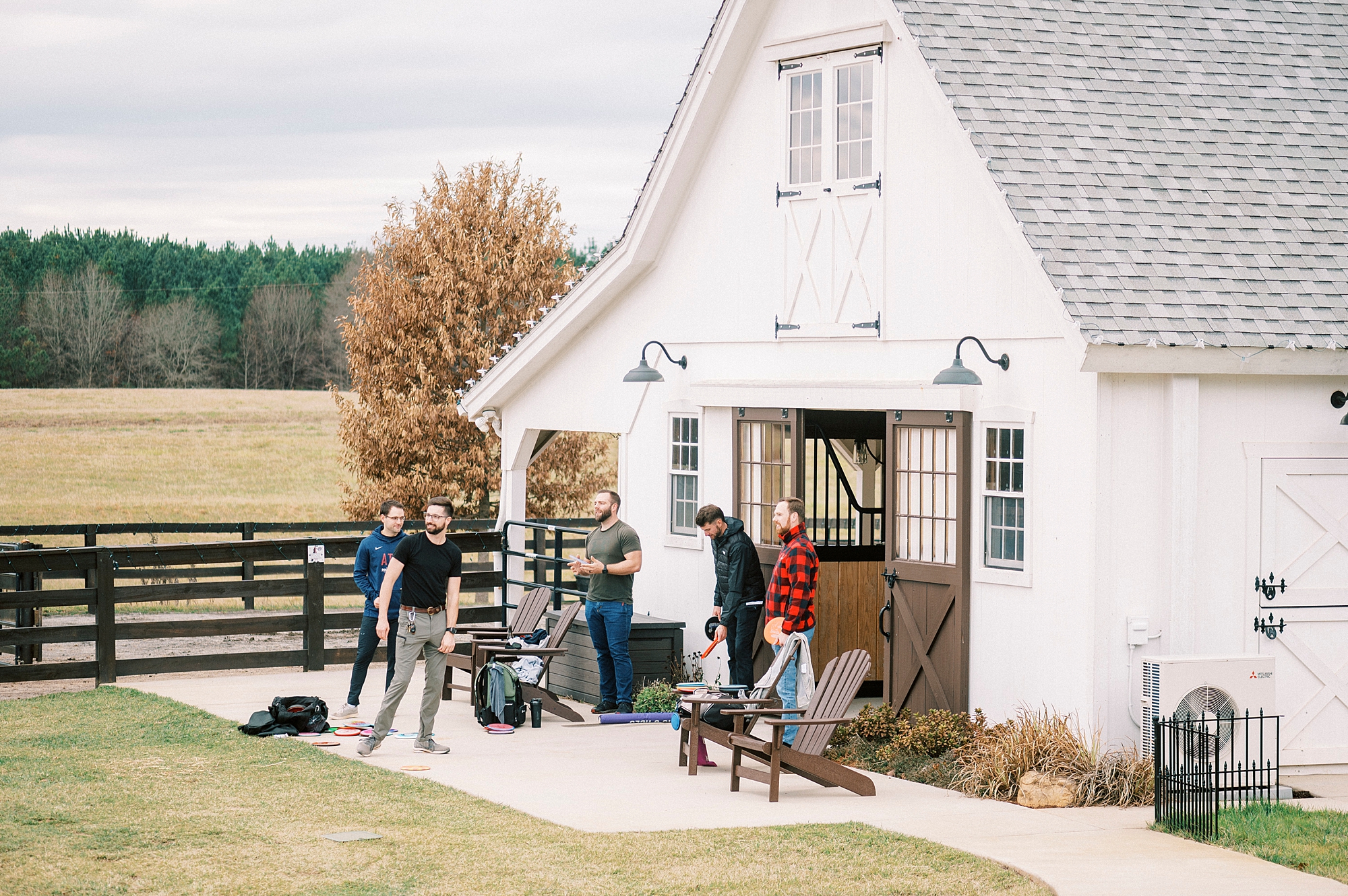 guests mingle on patio during cocktail hour outside barn at Chickadee Hill Farms