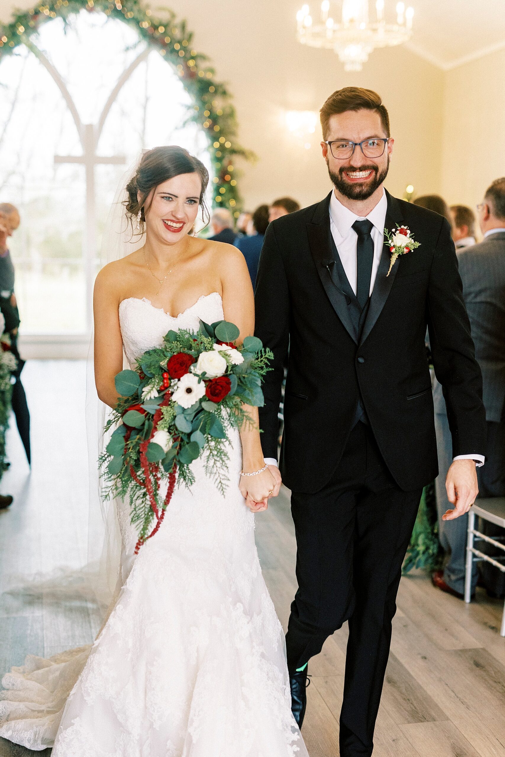 bride and groom grin walking up aisle inside chapel at Chickadee Hill Farms