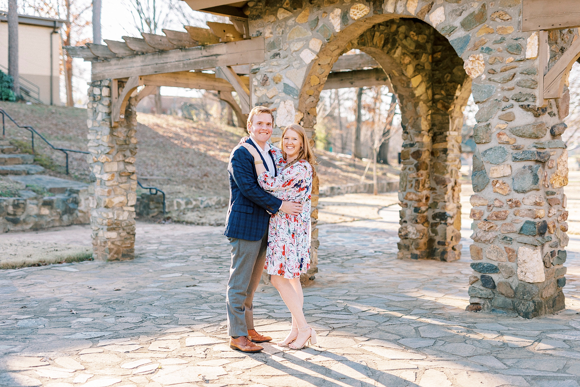man and woman hug inside Independence Park near stone archway