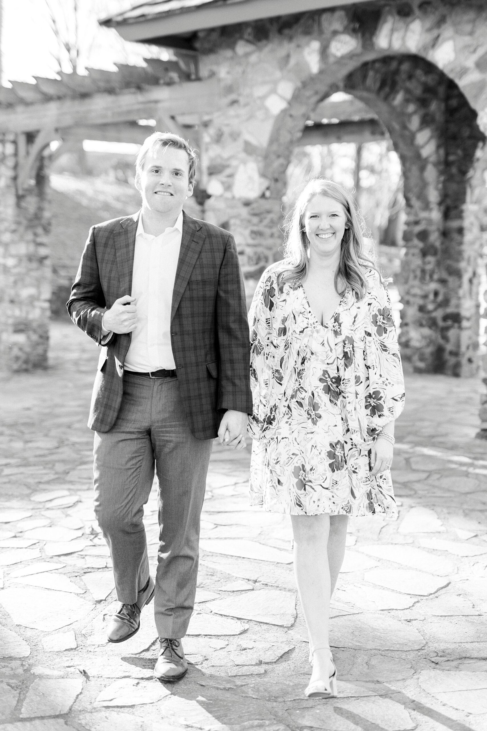 man and woman hold hands walking near stone arch at Independence Park