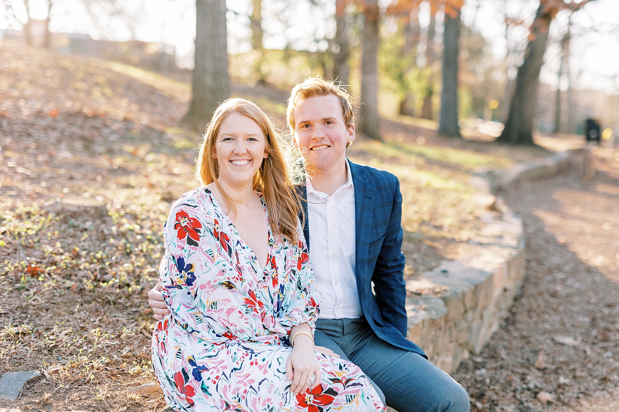 engaged couple sits on stone wall inside Independence Park during fall portraits