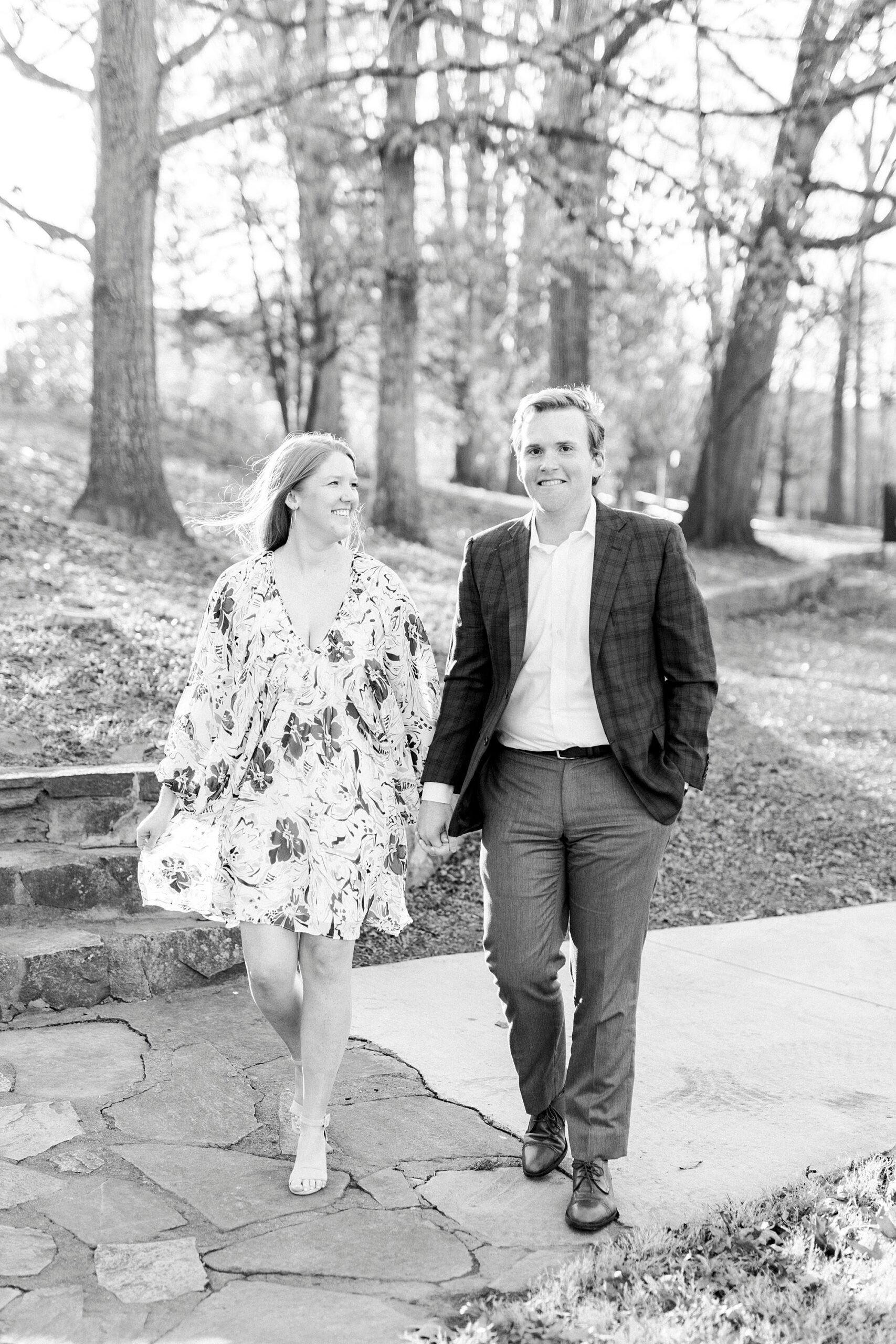 couple holds hands walking on stone pathway inside Independence Park