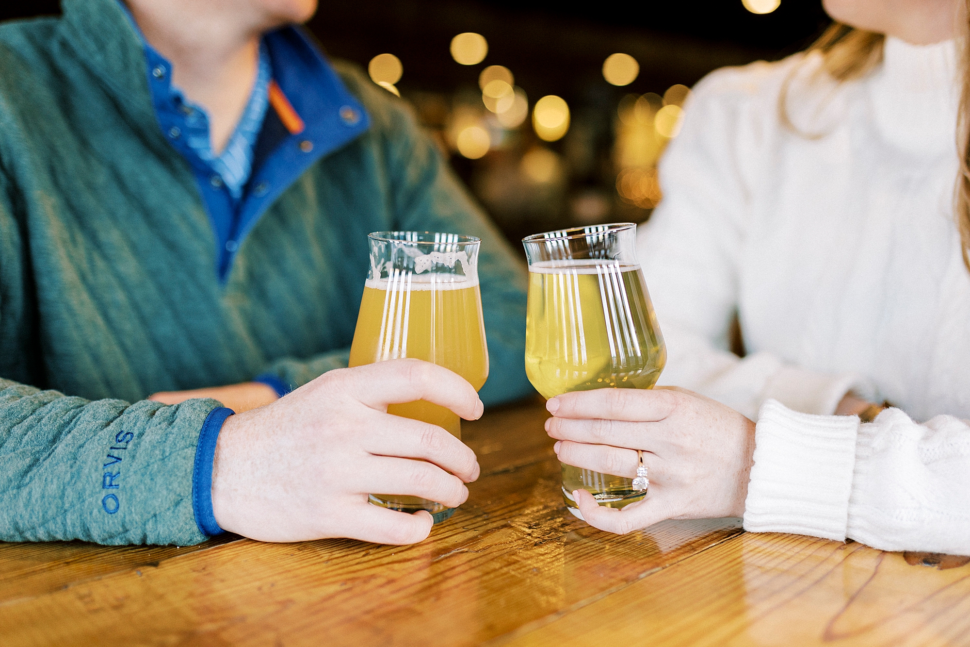 couple leans pints of beer together at Legion Brewing in Charlotte NC