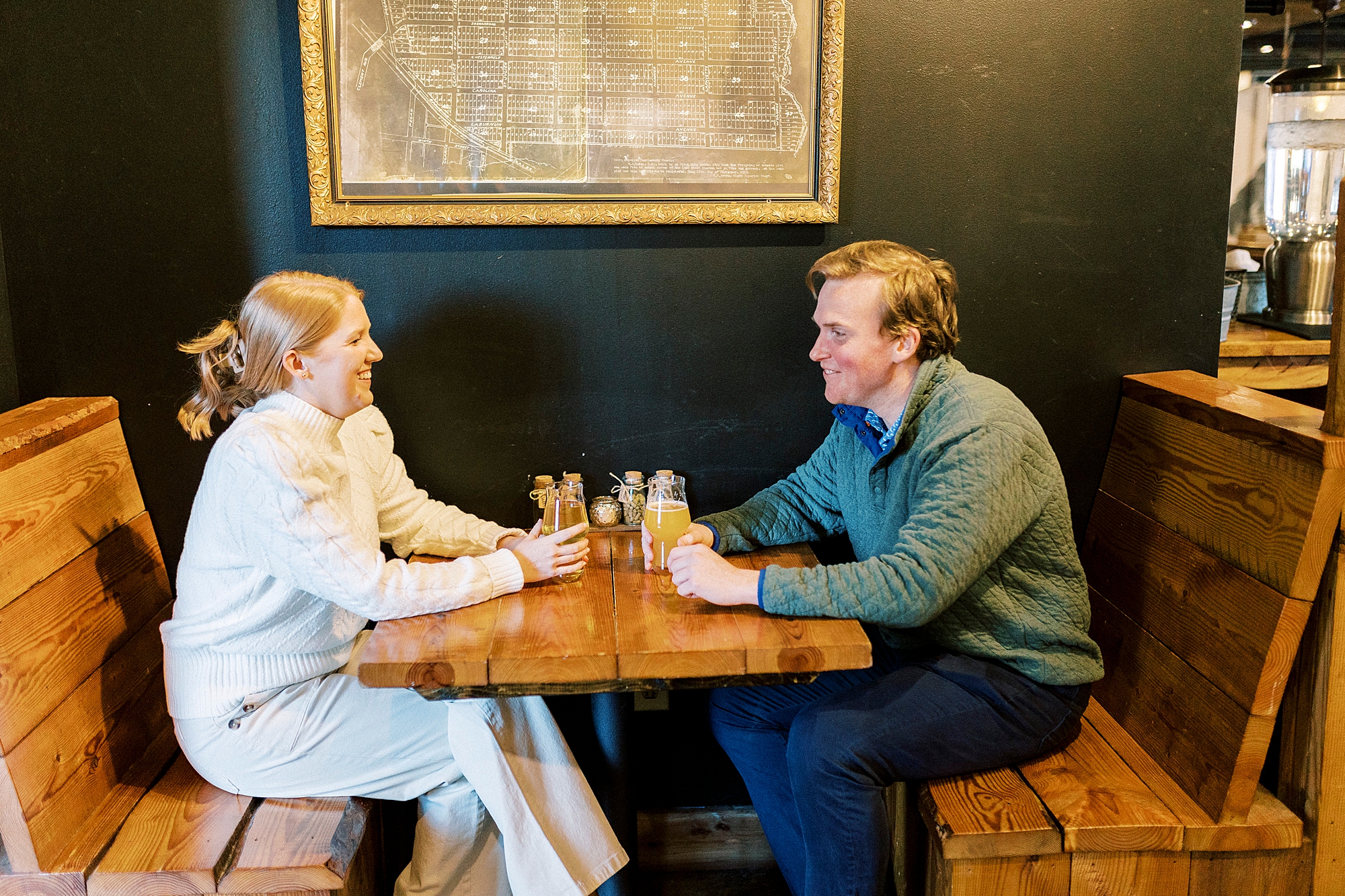 couple sits talking at table during date at Legion Brewing in Charlotte NC