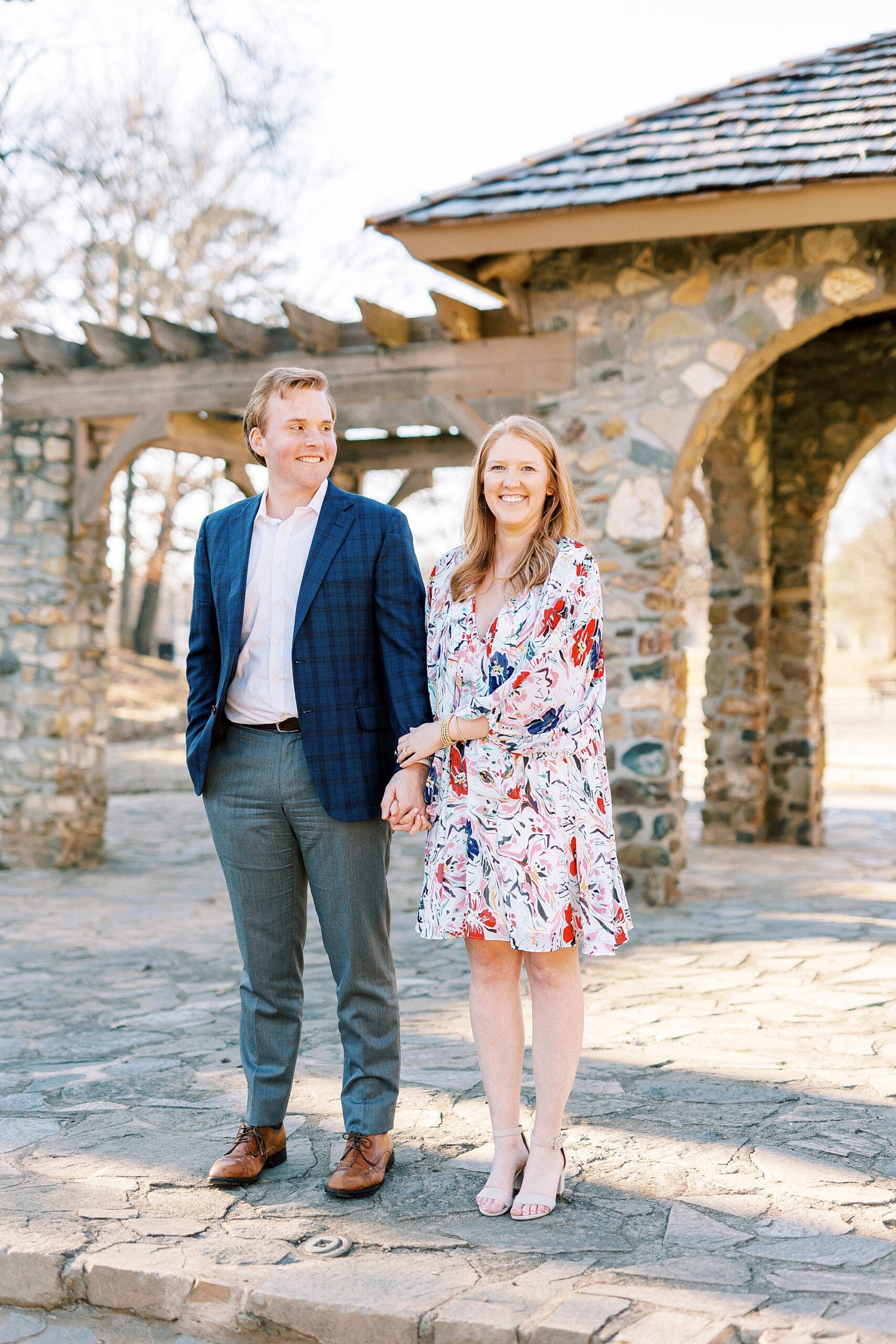 couple holds hands walking in front of stone patio at Independence Park