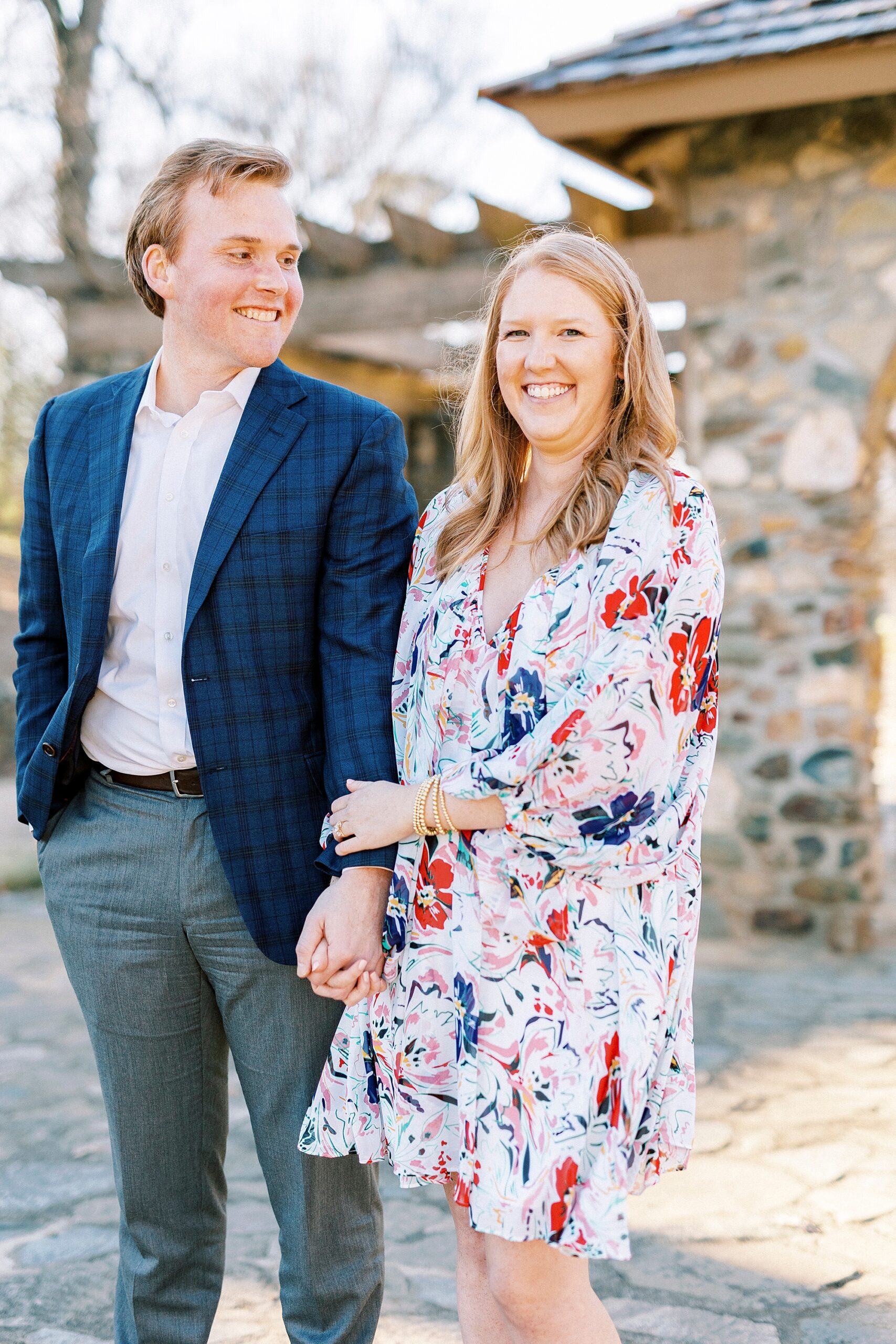 man and woman hold hands in front of stone archway inside Independence Park in Charlotte NC