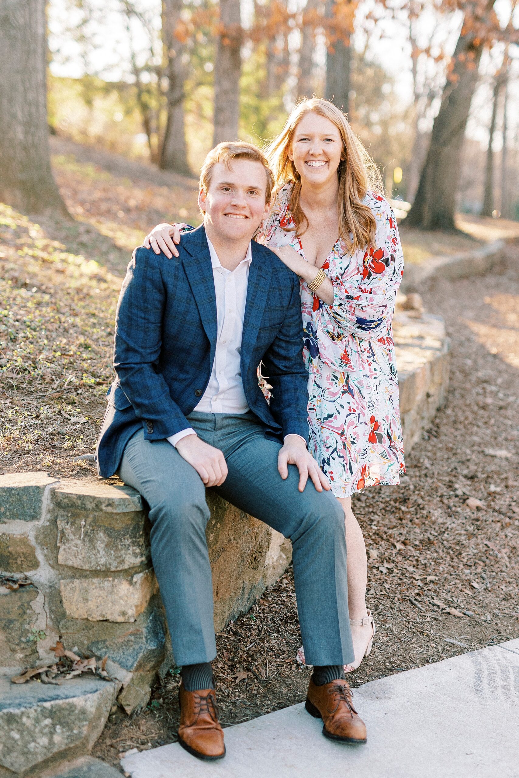 couple sits on stone wall inside Charlotte NC park