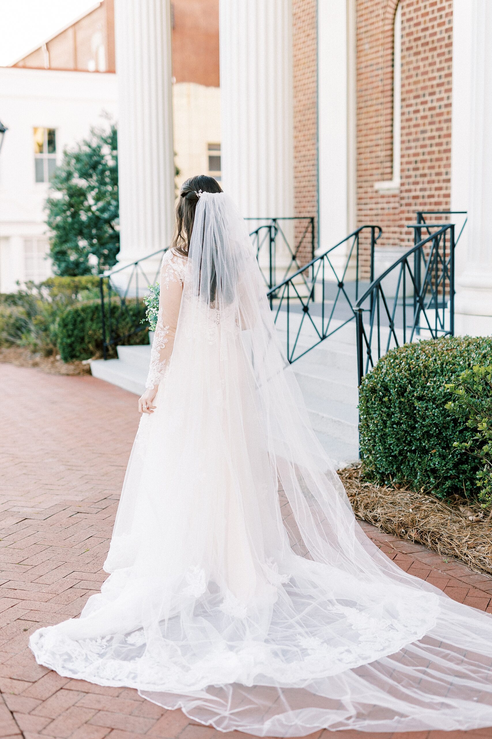 bride walks towards church during bridal portraits in Downtown Kannapolis