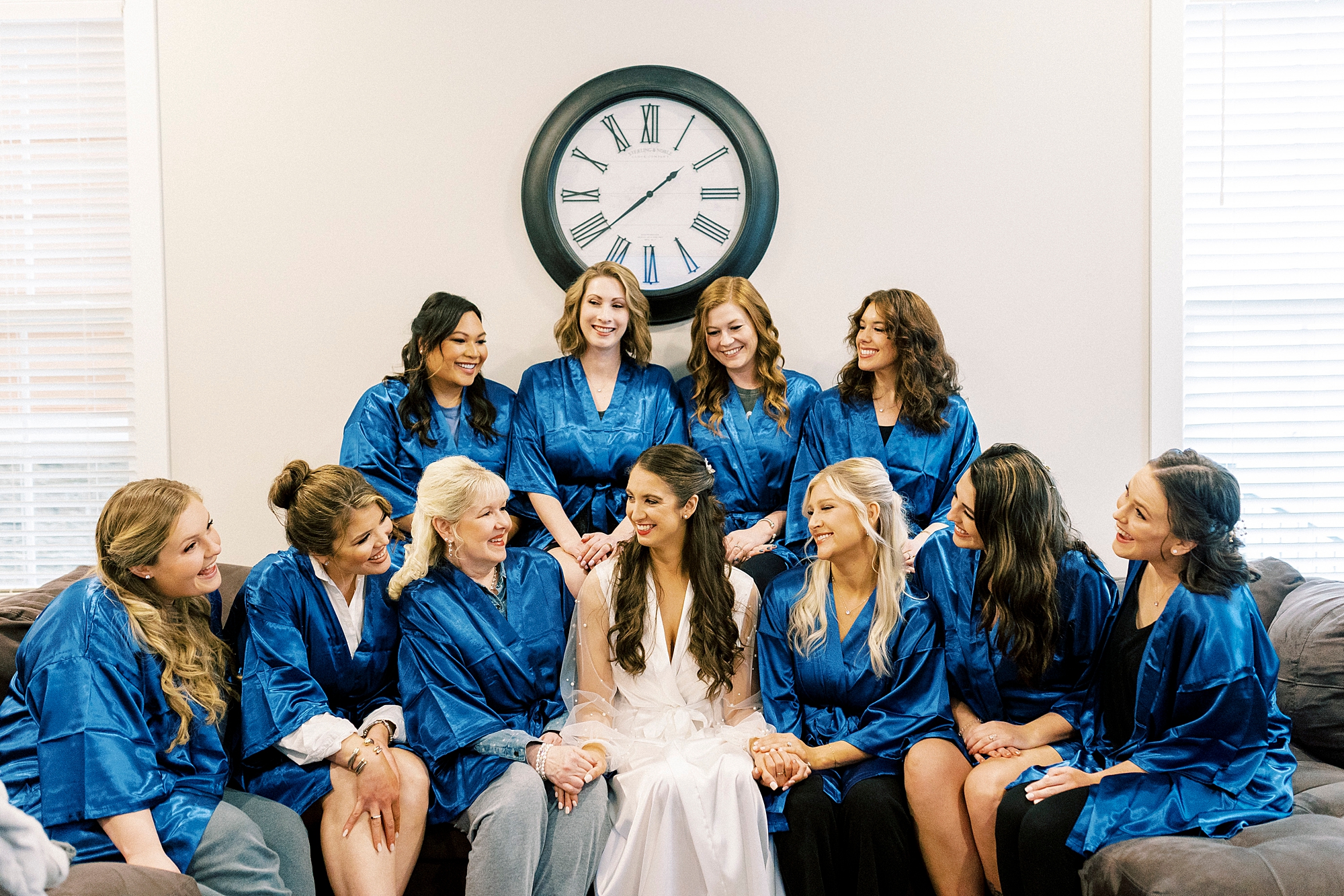 bridesmaids in blue silk robes sit around bride before Downtown Kannapolis wedding