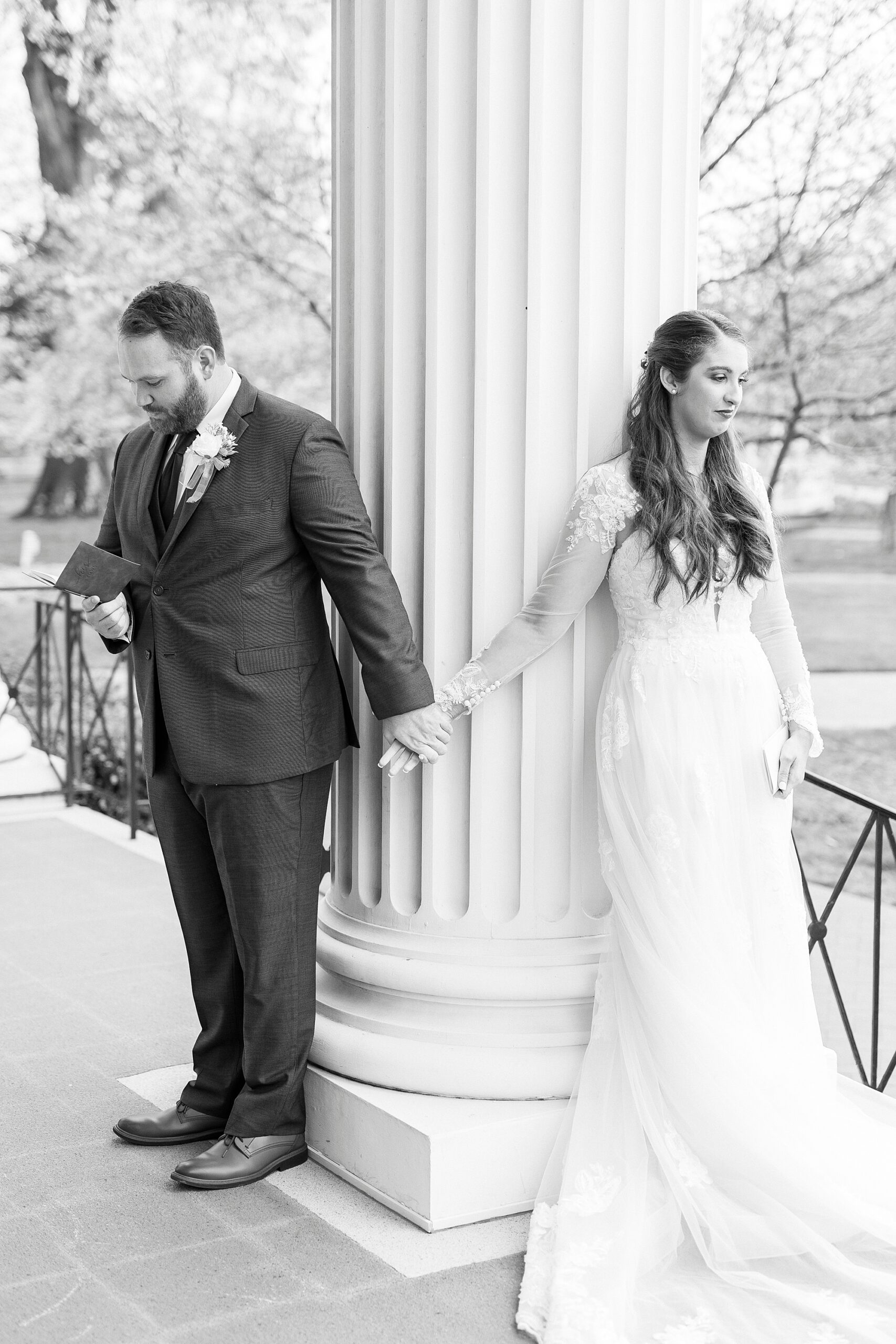 bride and groom hold hands around column during first touch