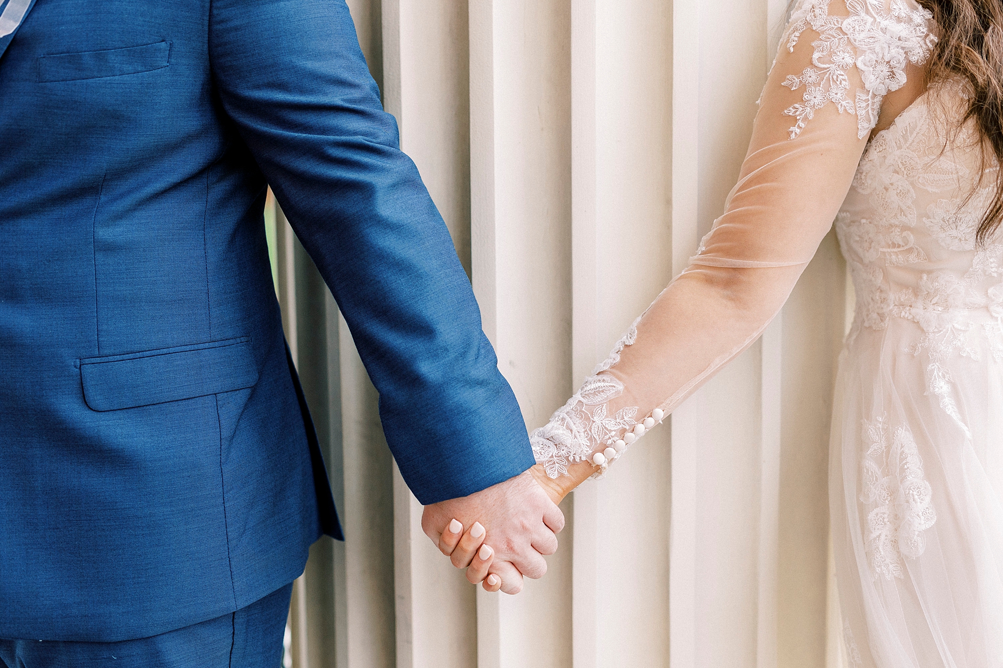 bride and groom hold hands by column outside First Baptist Church in Kannapolis NC