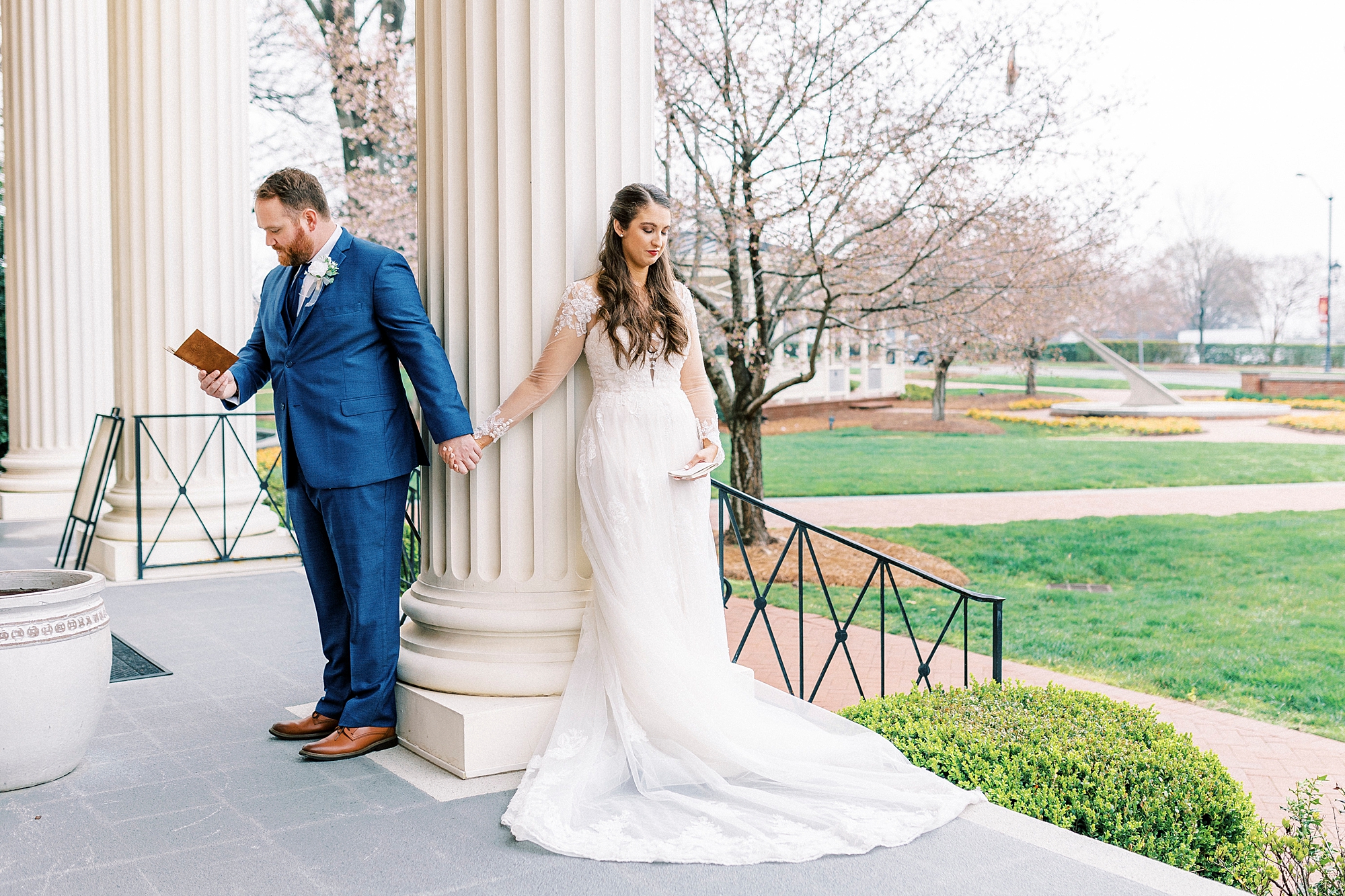 newlyweds hold hands around column outside First Baptist Church in Kannapolis NC for first touch