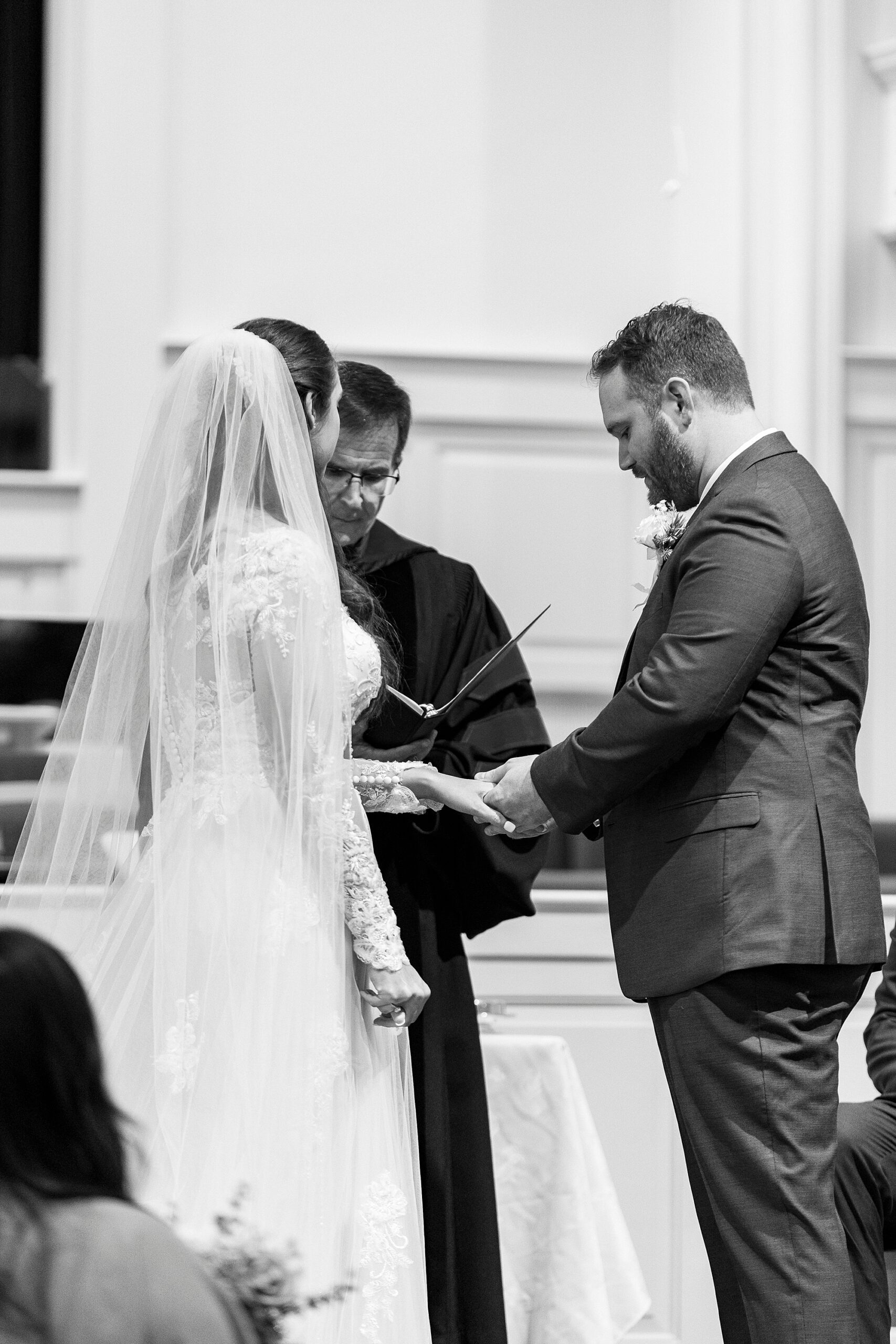 bride and groom hold hands bowing head inside First Baptist Church in Kannapolis NC