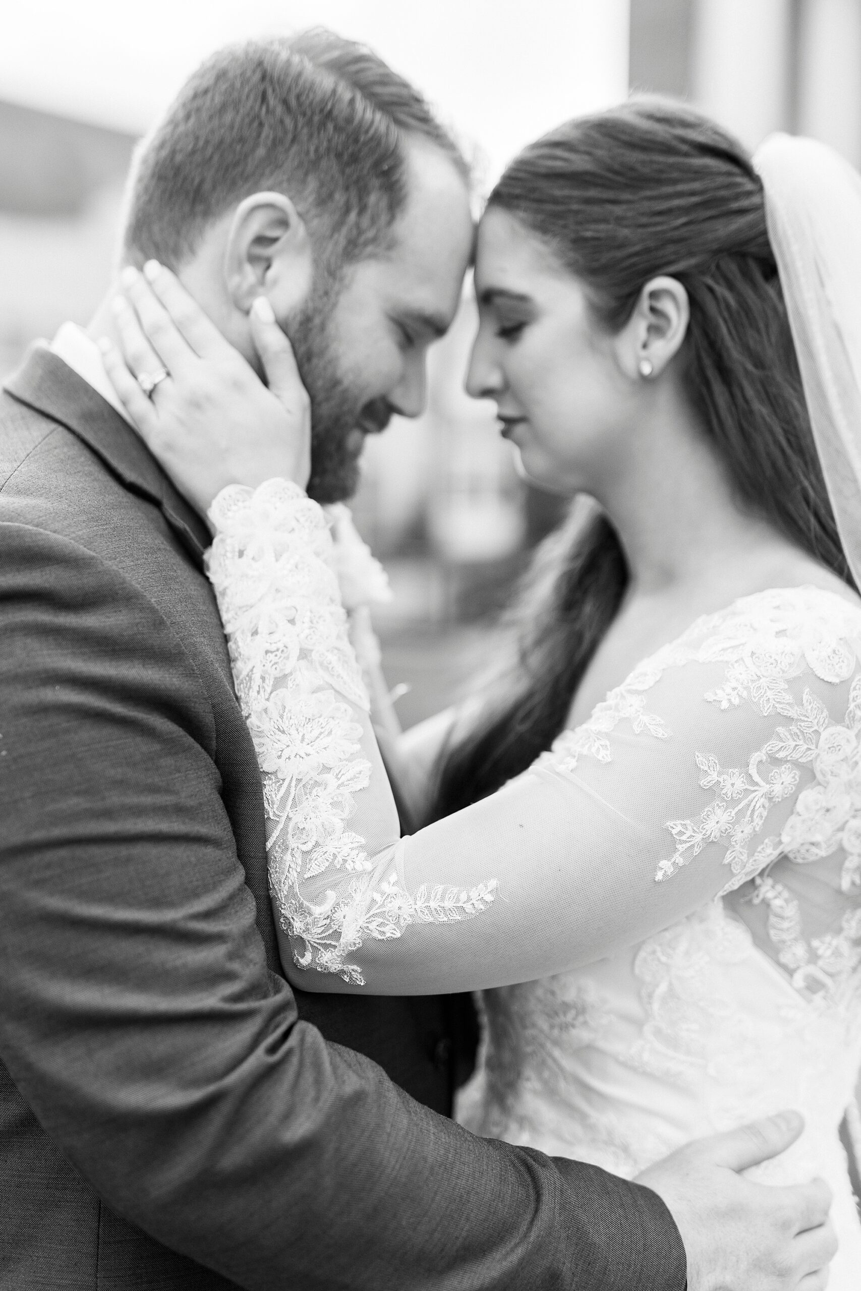 newlyweds lean heads together while bride holds groom's neck