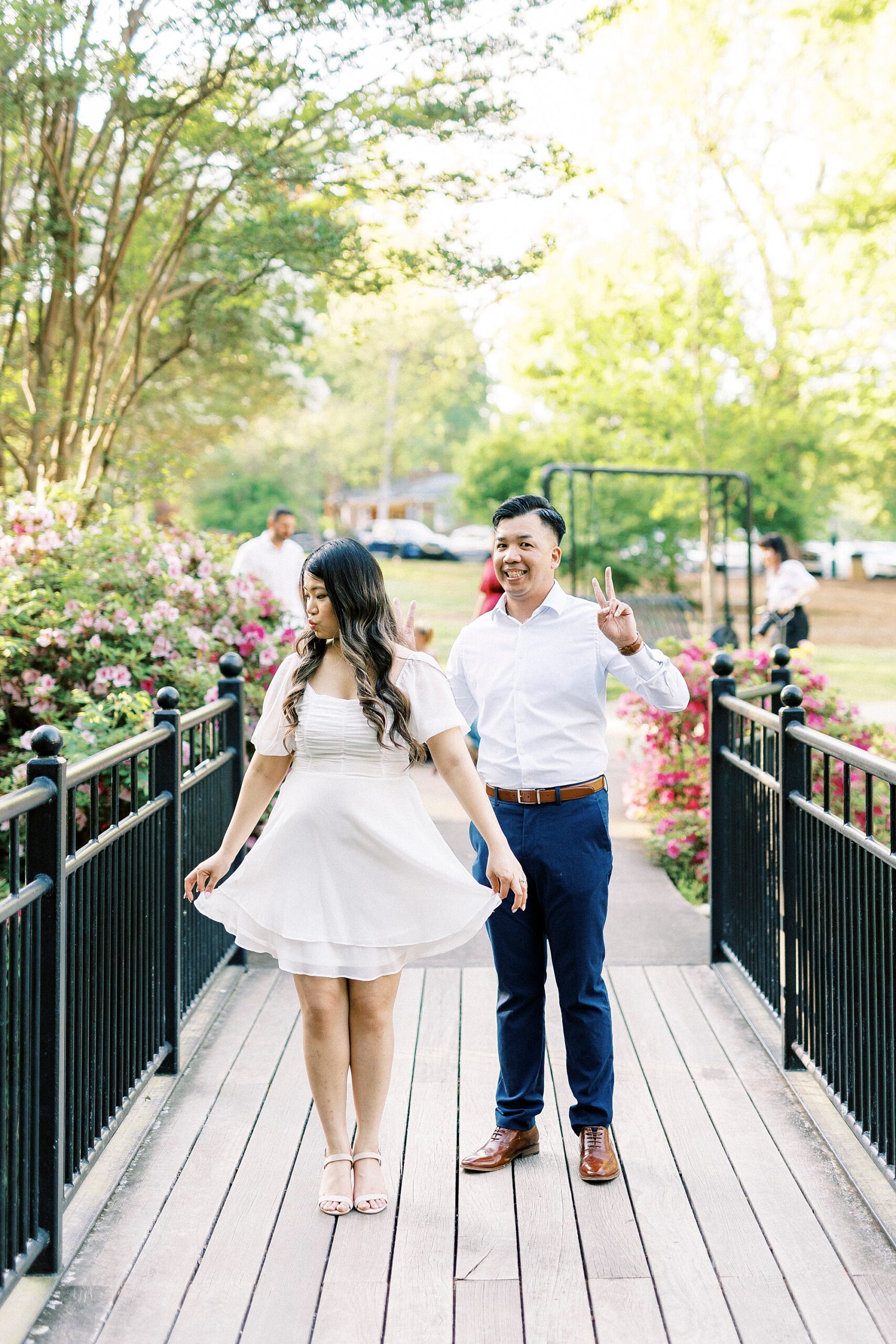 couple walks on bridge while guests mingle behind them 