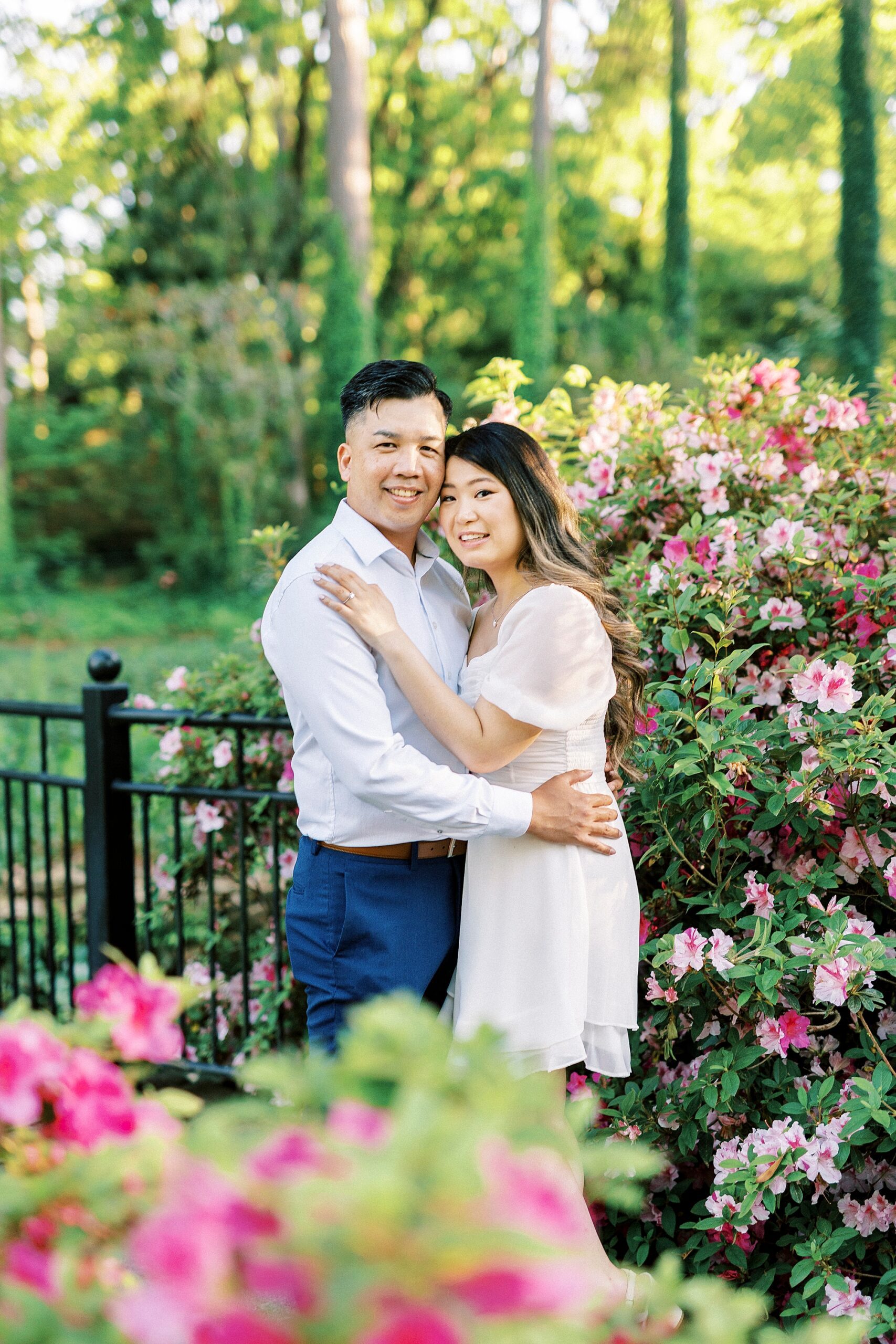 woman hugs man inside garden of pink flowers at Glencairn Garden