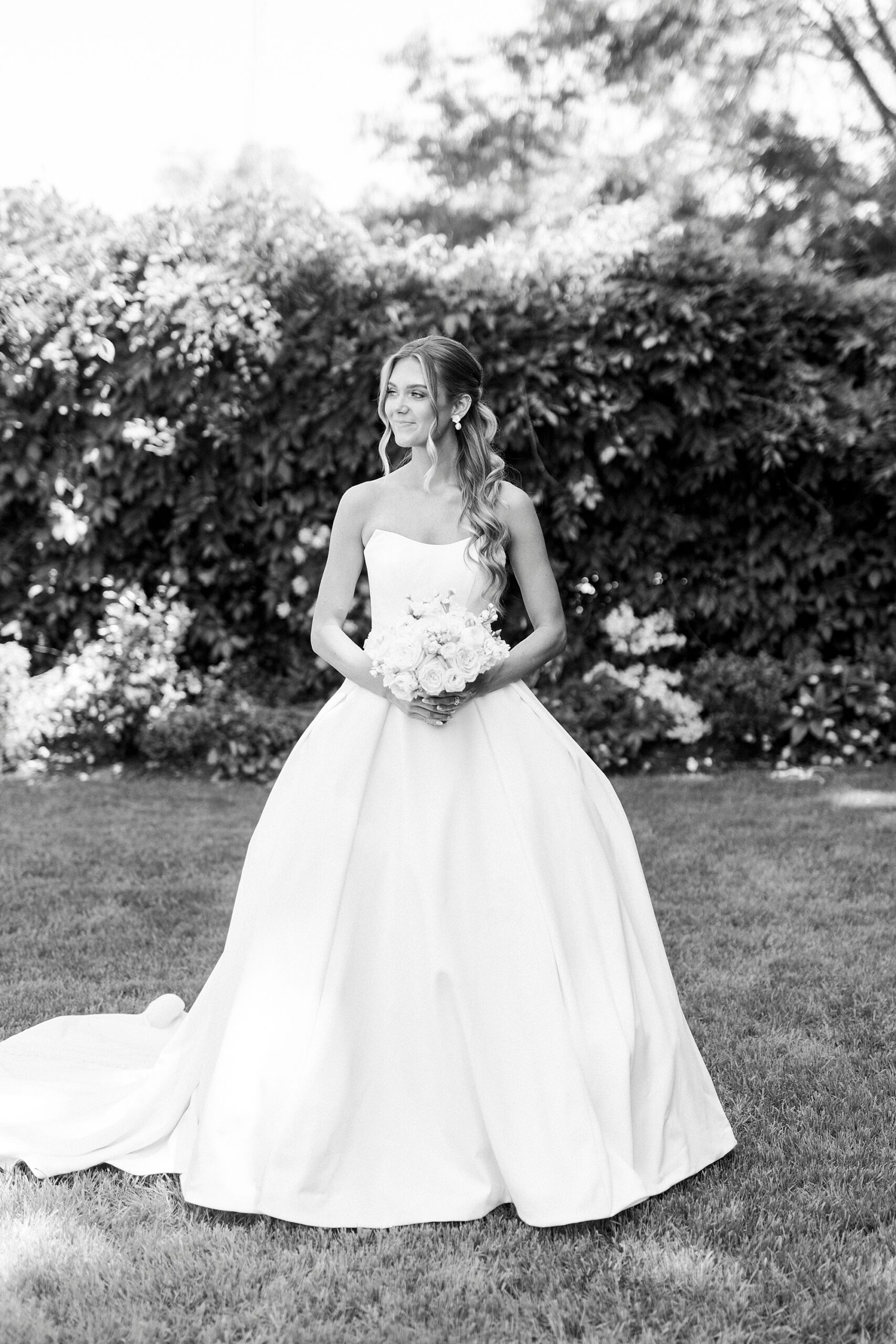 bride stands in gardens of Separk Mansion holding hands in front of her dress