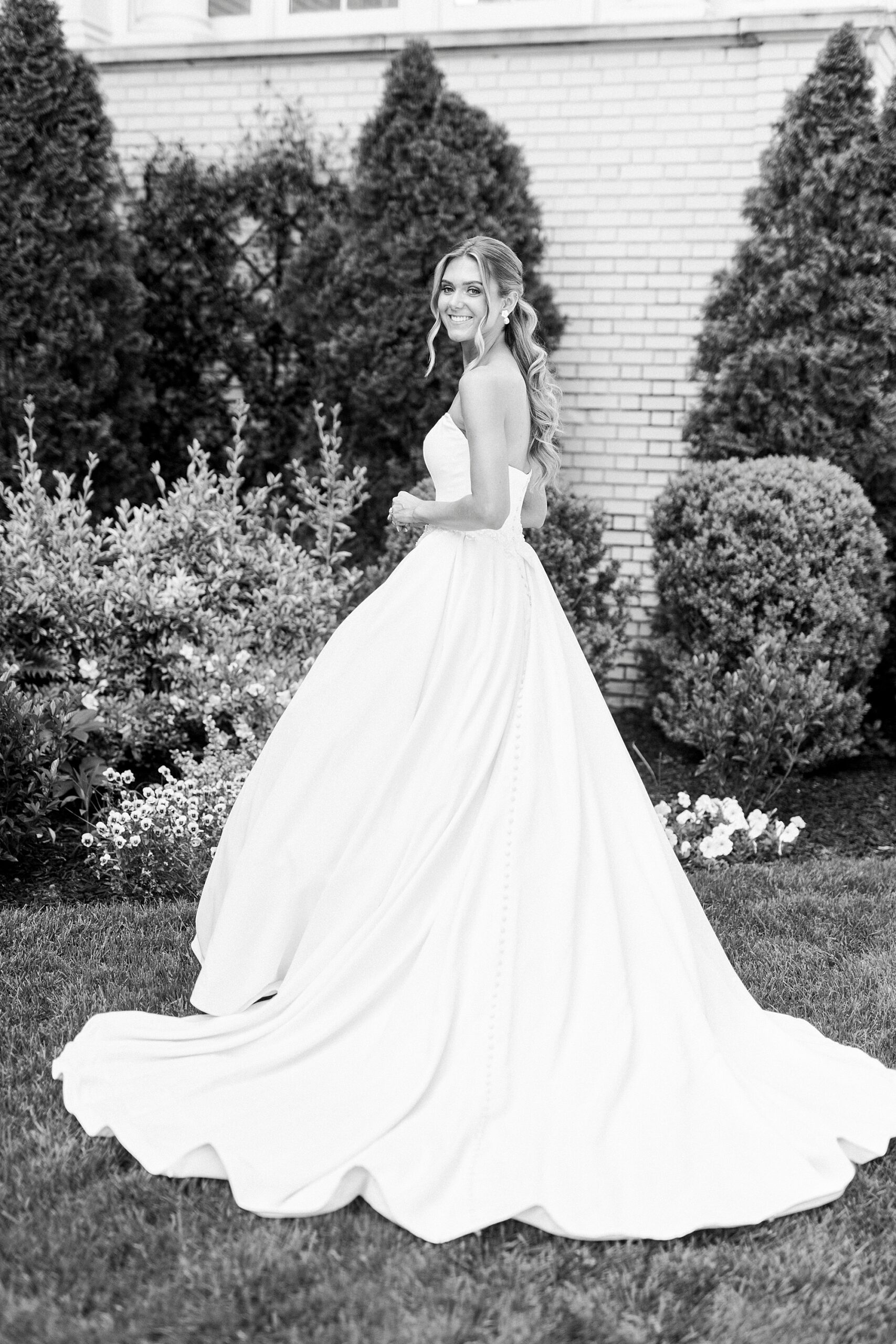 bride stands looking over shoulder in strapless gown