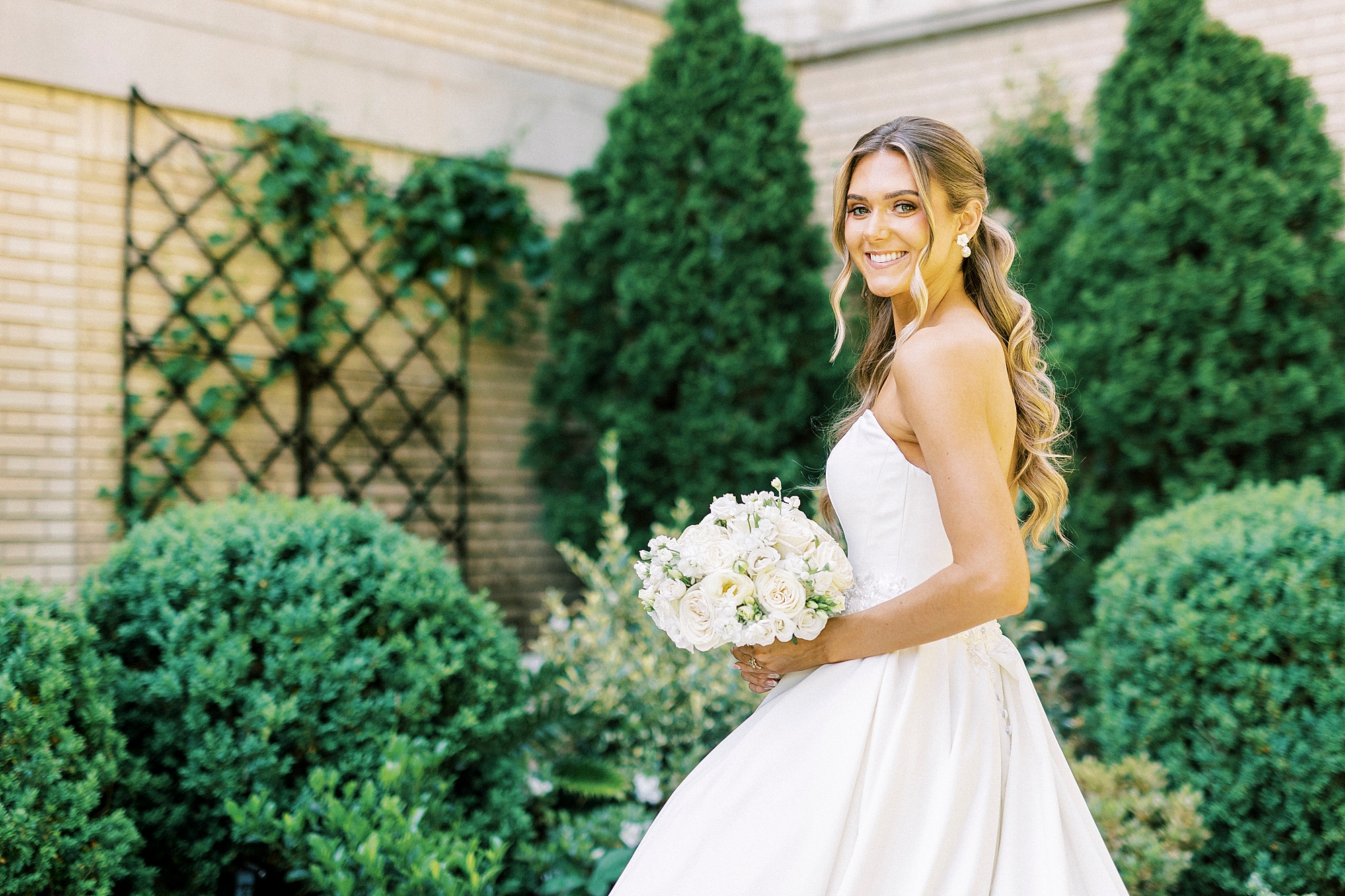 bride smiles holding bouquet of white flowers in strapless gown at Separk Mansion