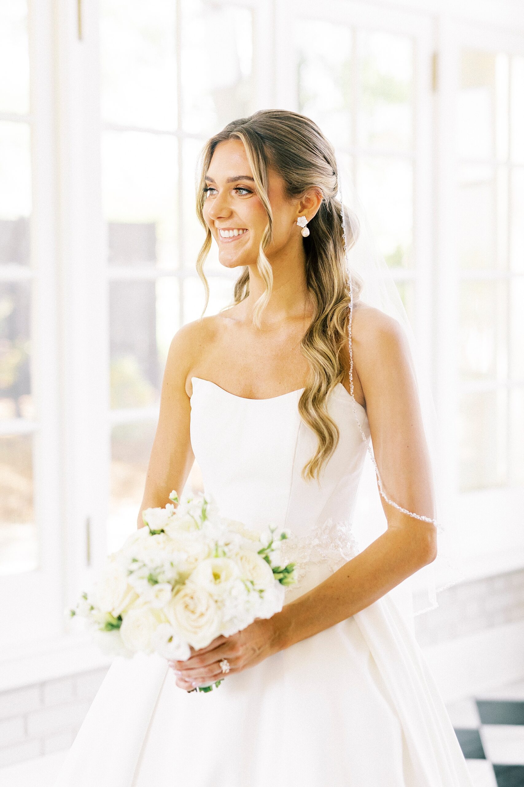 bride holds bouquet of ivory flowers in sunroom at Separk Mansion