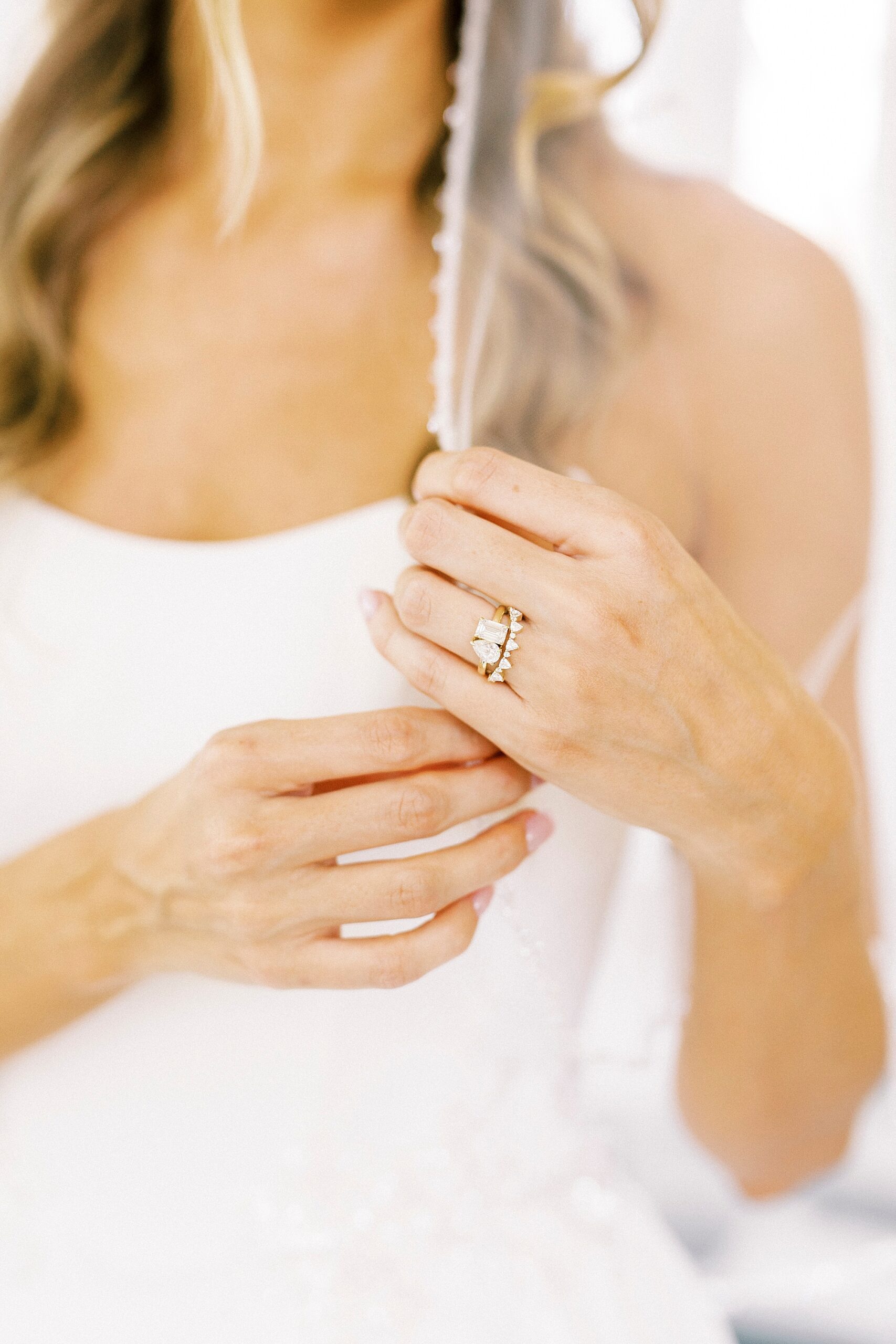bride holds edge of veil showing off engagement ring