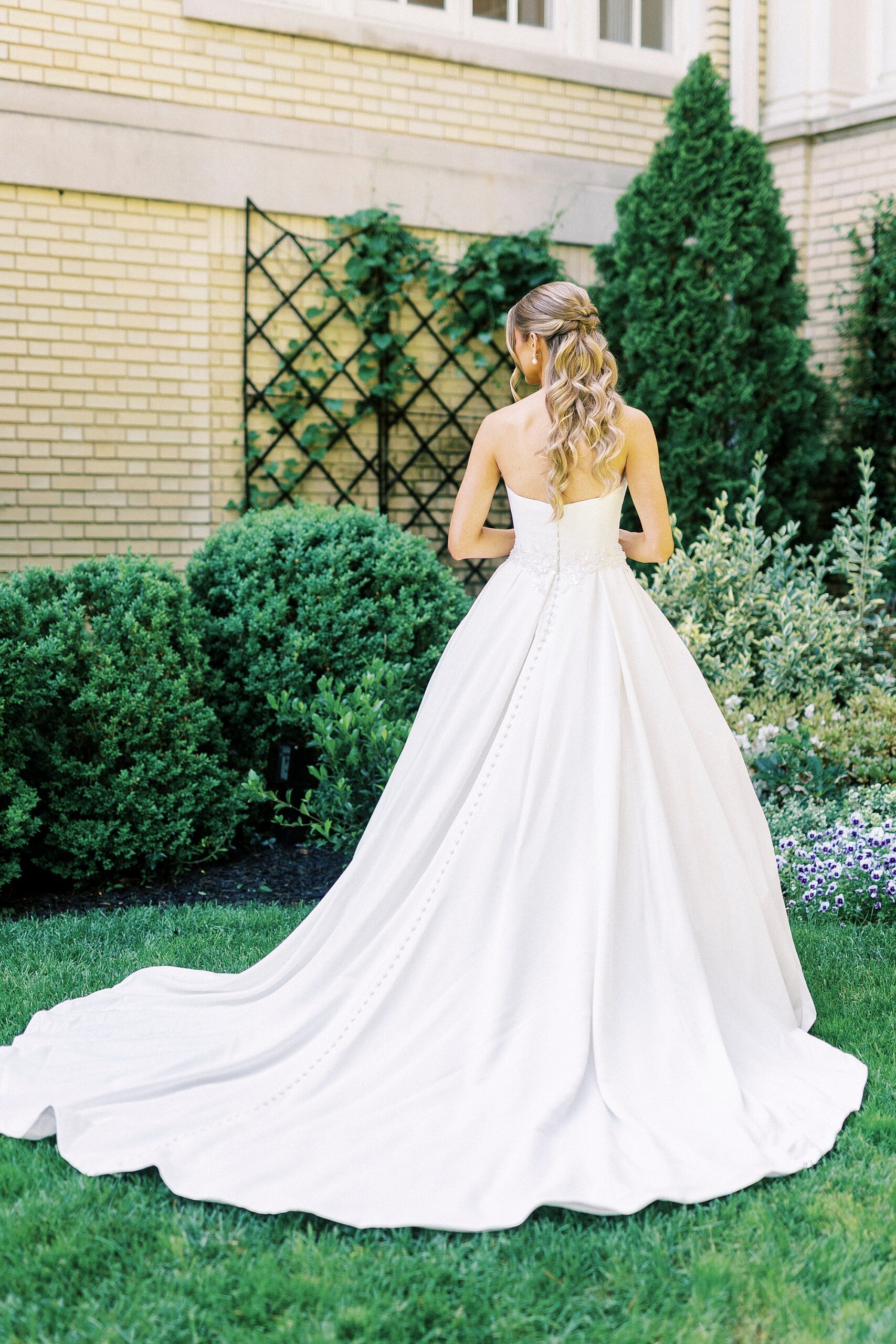 bride looks over her shoulder showing off back of wedding gown