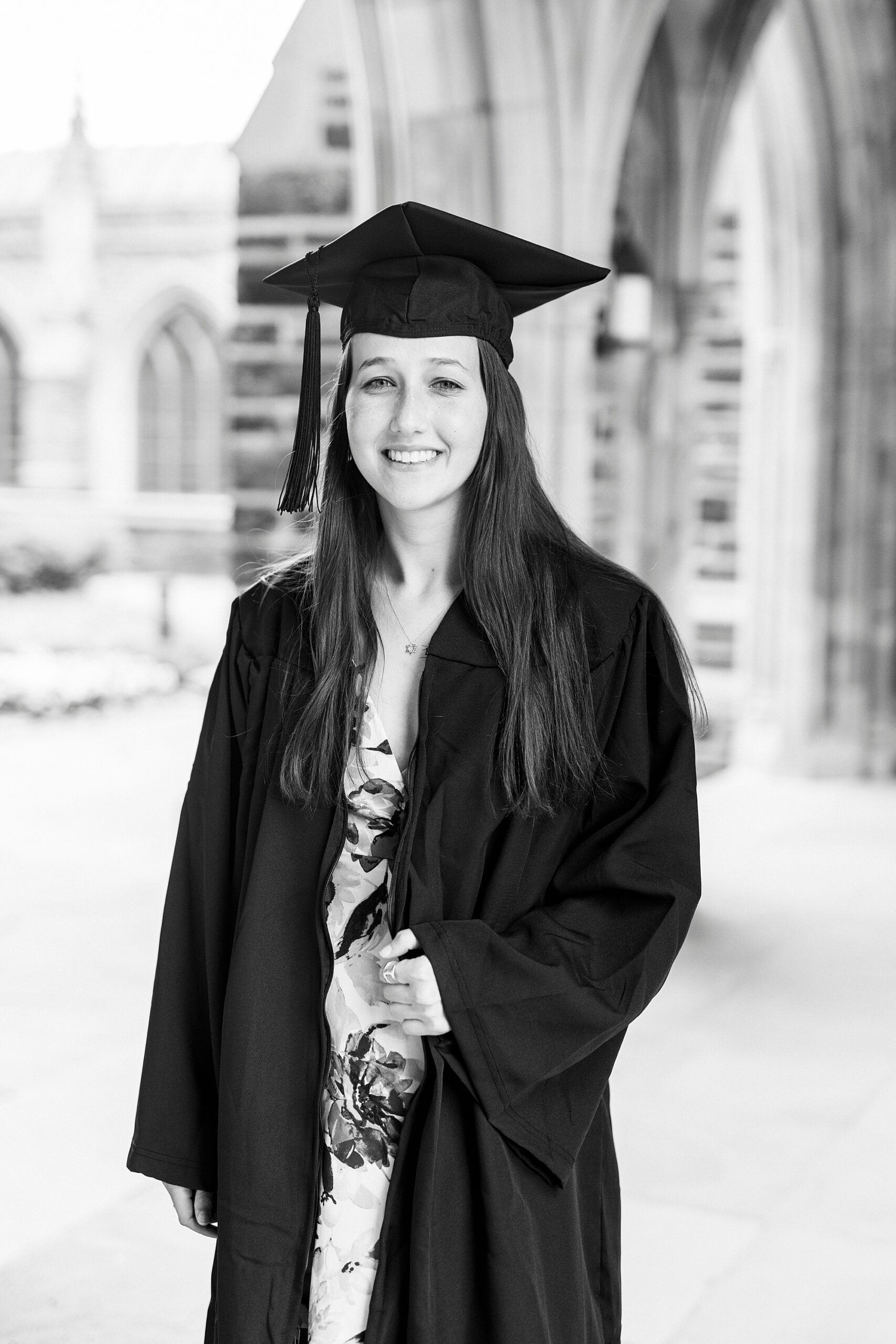 Duke University graduate poses in cap and gown in front of Duke University chapel