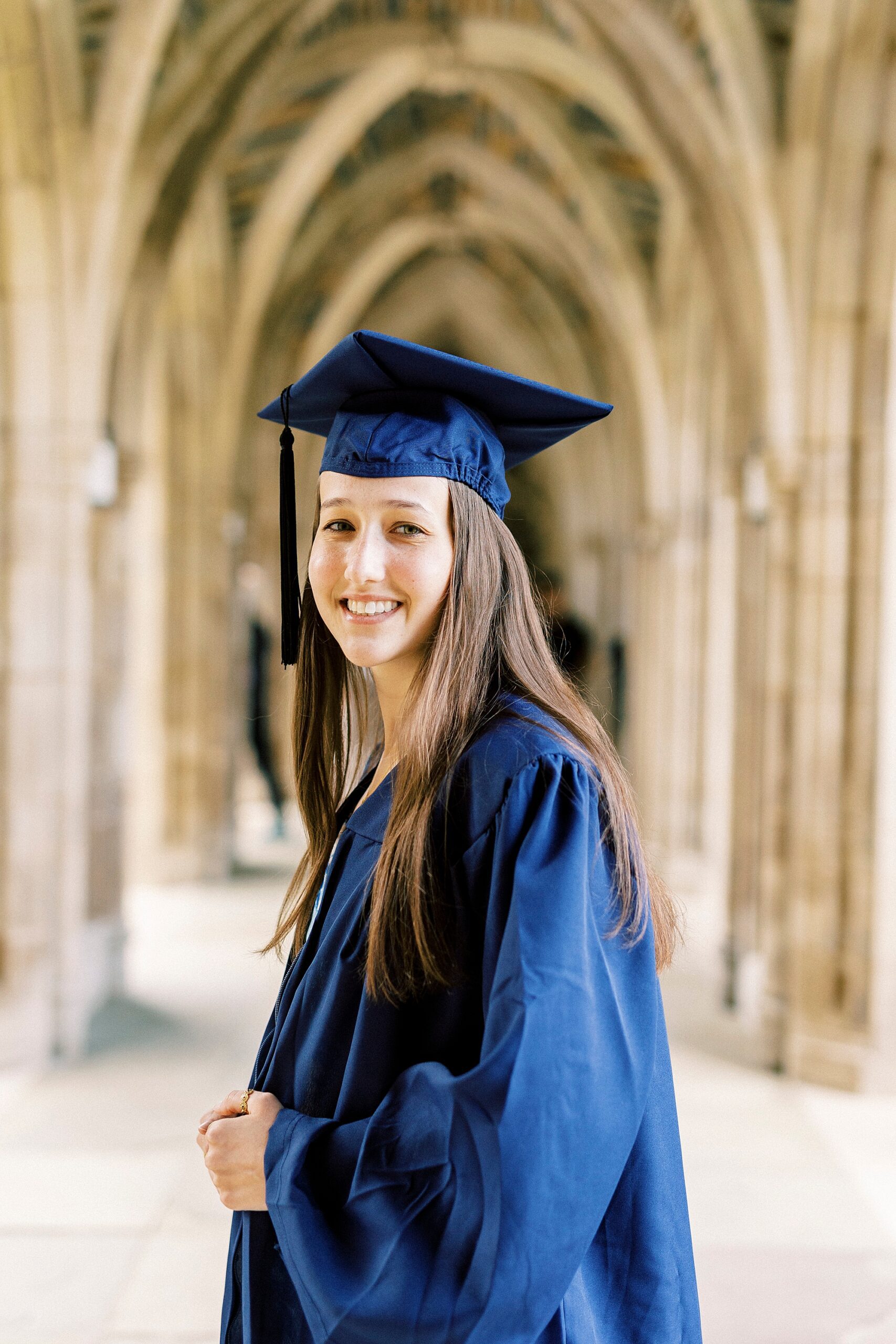 girl smiles in cap and gown during Duke University senior portraits