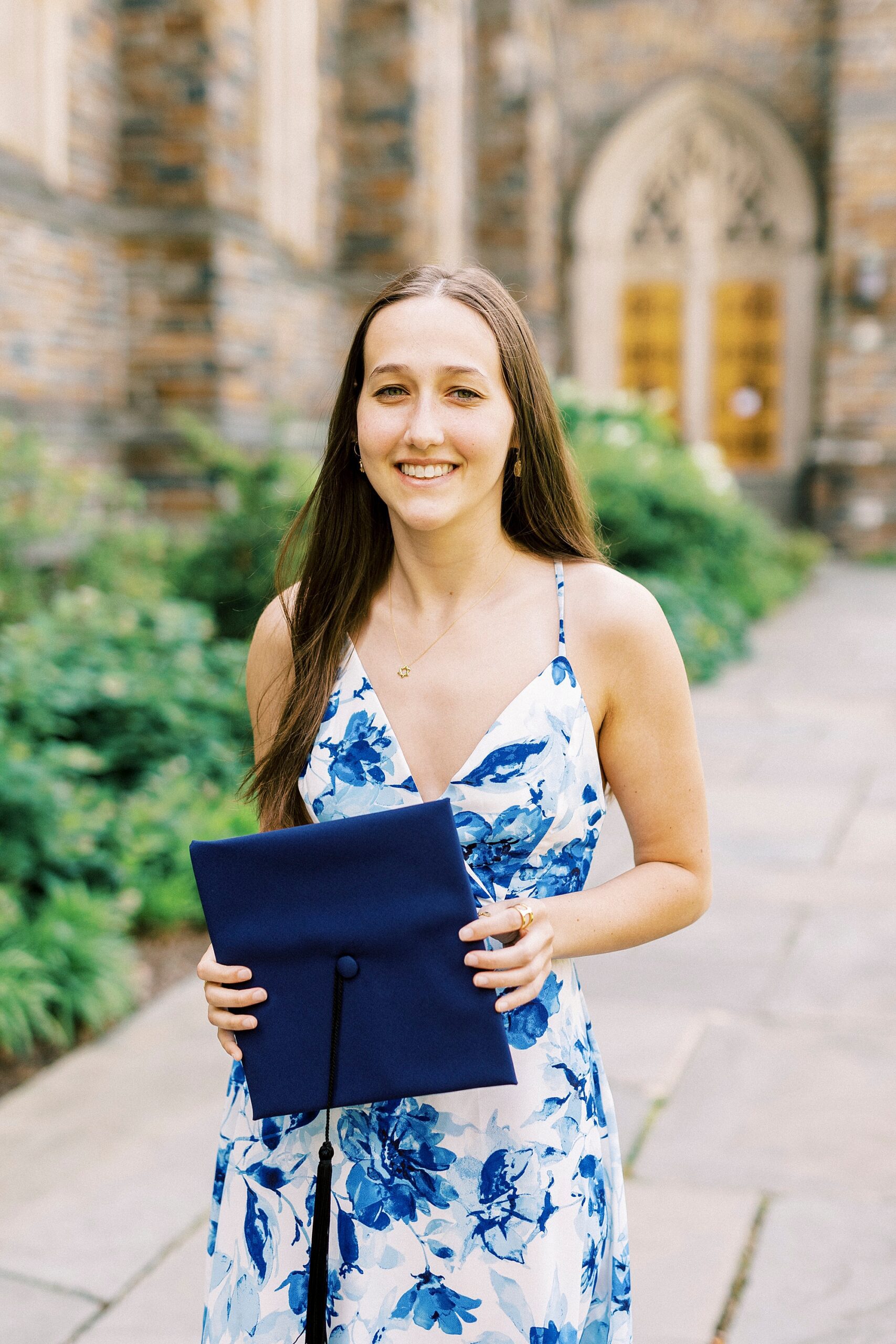 senior holds blue cap in front of her during Duke University senior portraits