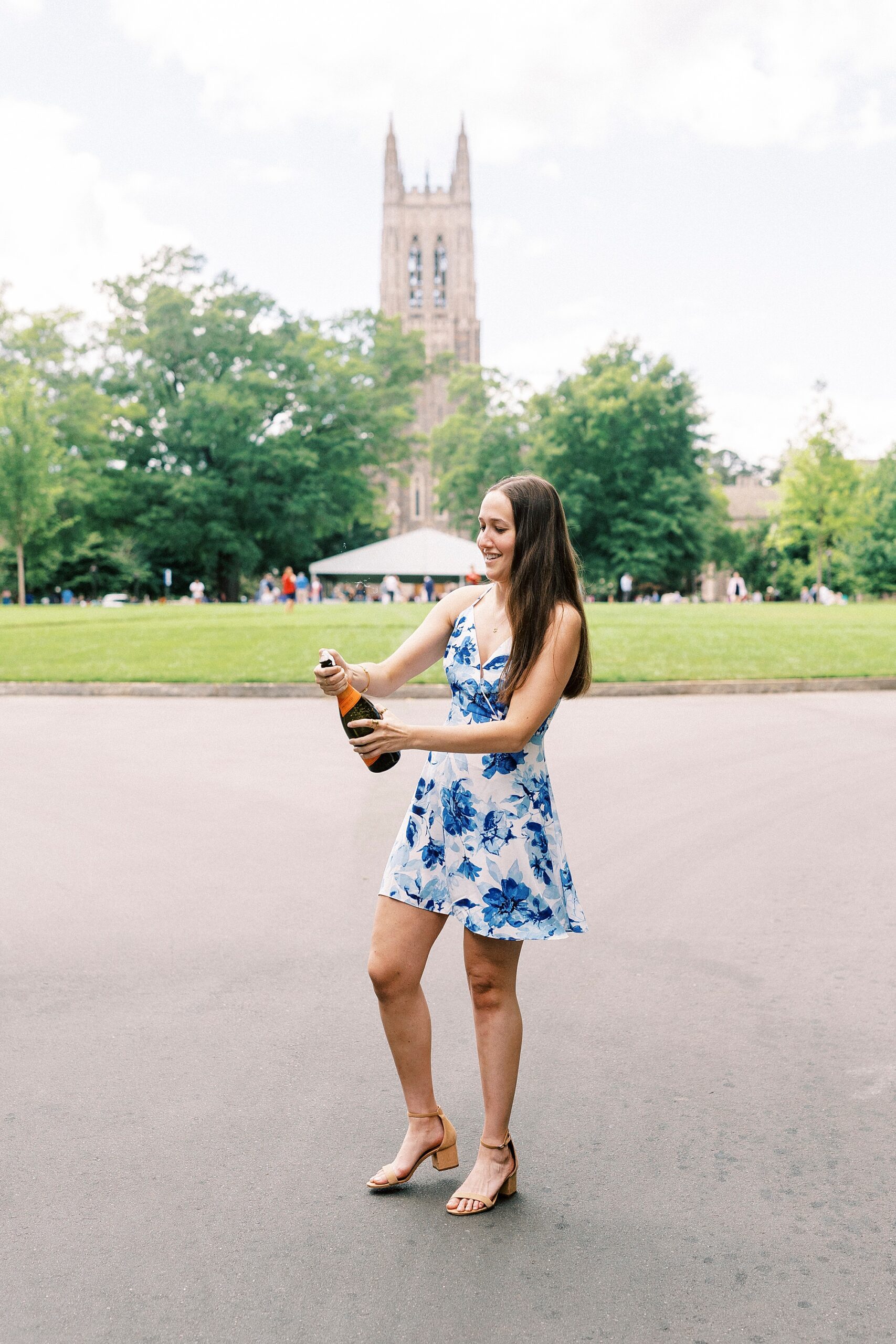 girl in blue and white dress pops champagne bottle 