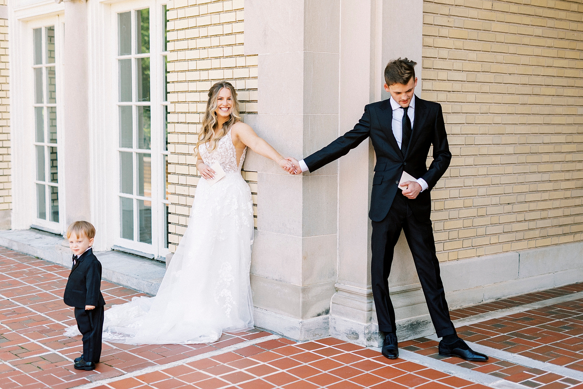 man and woman hold hands around corner of Separk Mansion with son in front of bride