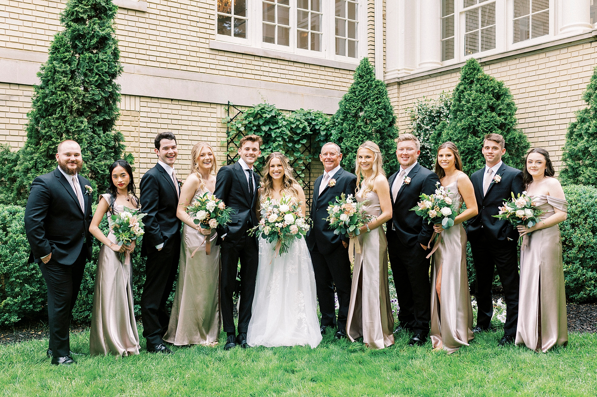 bride and groom stand with wedding party on spring wedding day
