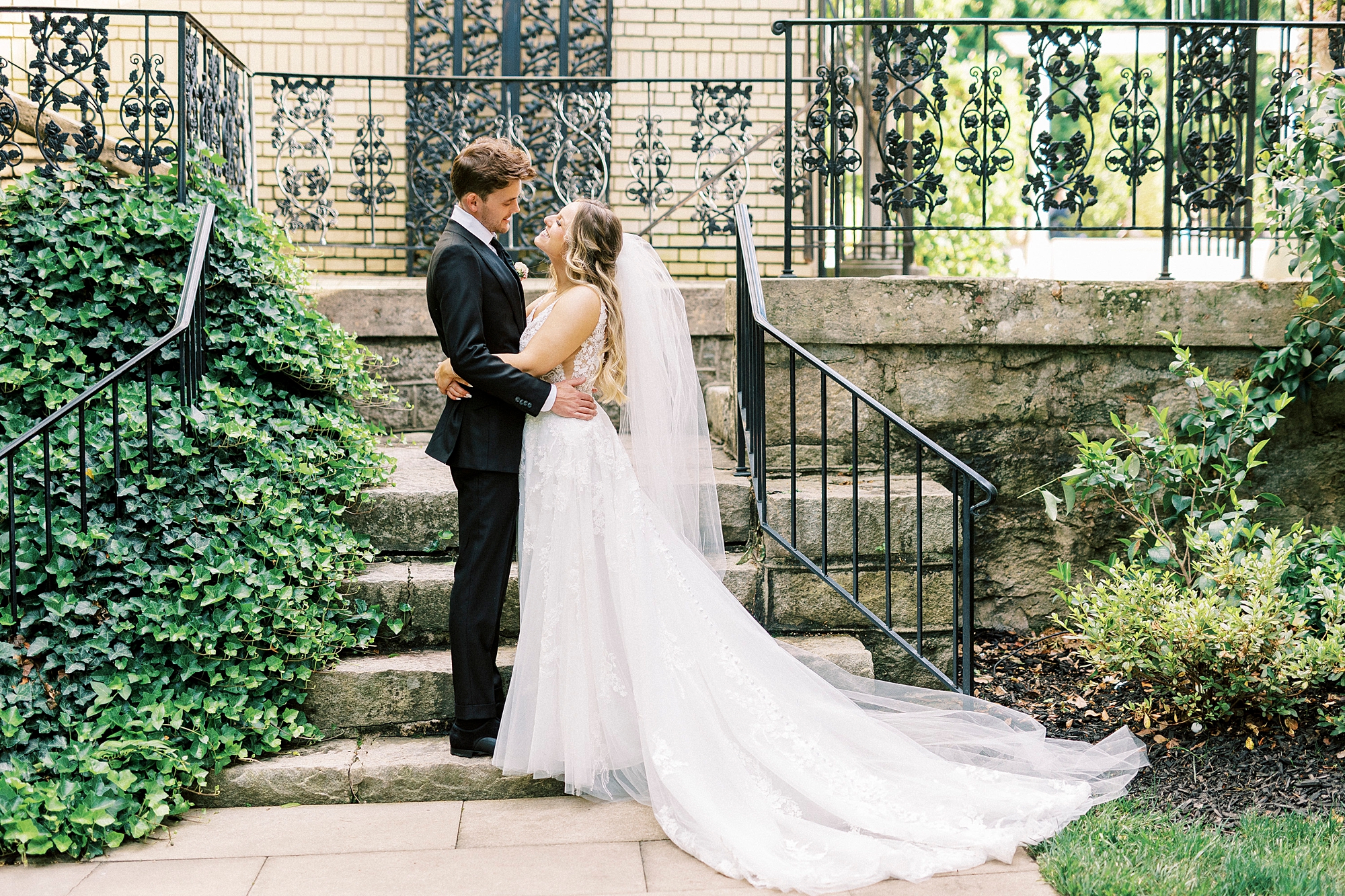 bride looks up at groom hugging him near stone steps inside Separk Mansion