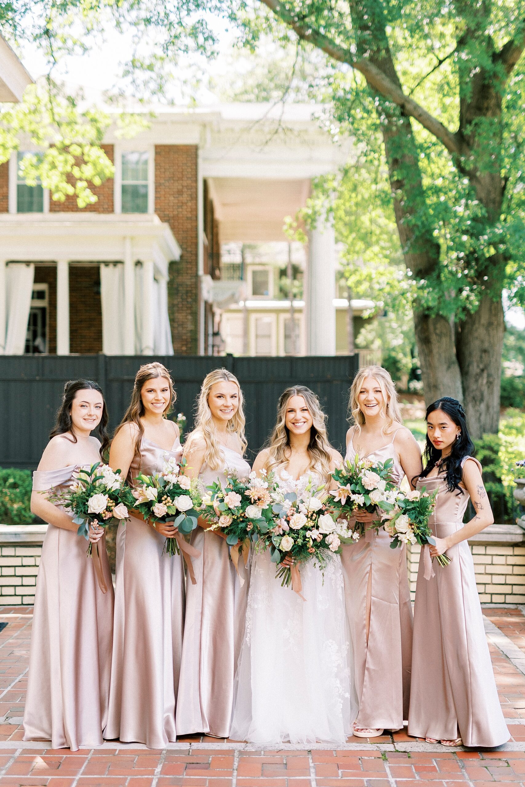 bride stands with bridesmaids in silk pink dresses 