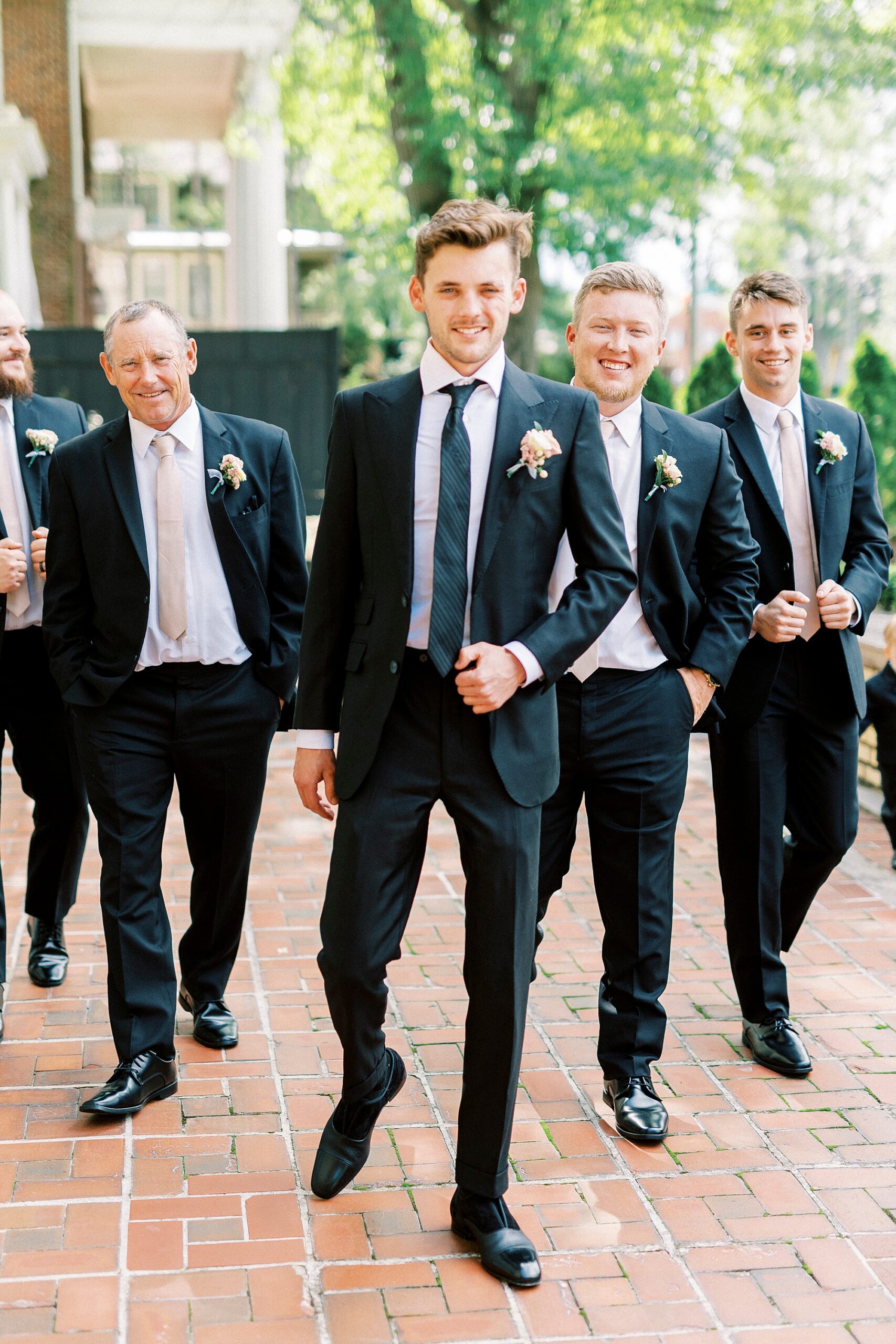 groom walks with groomsmen in matching black suits 