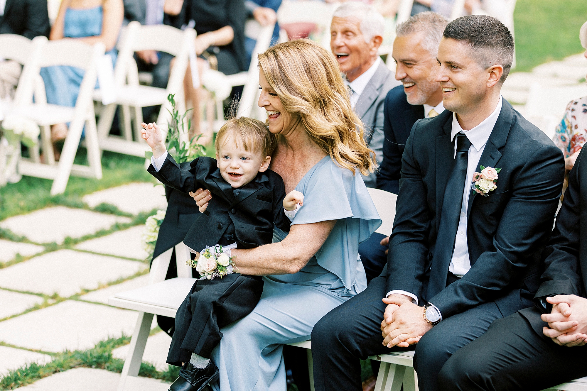 mother of the bride holds grandson on lap during ceremony 