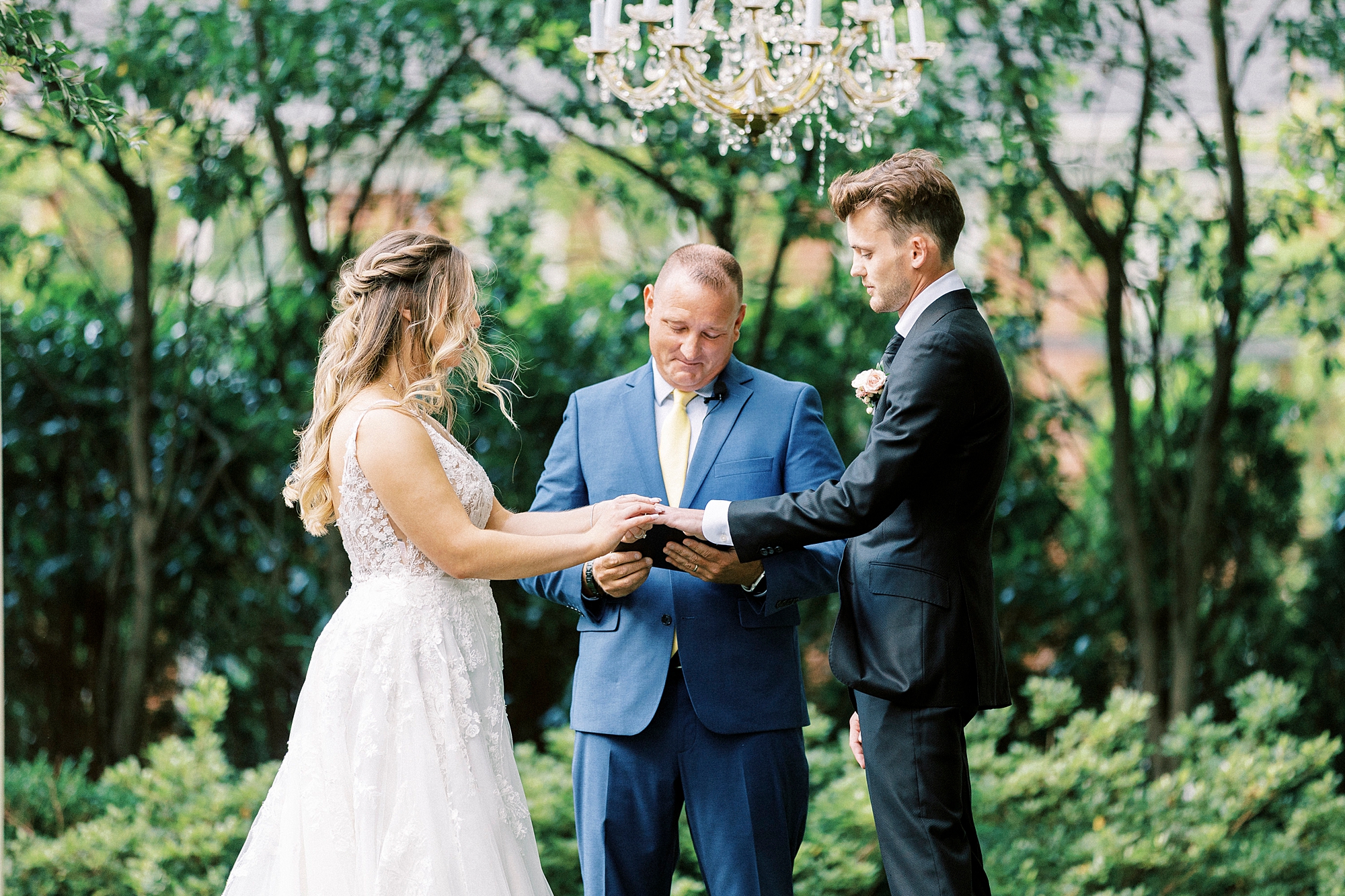 bride and groom hold hands under arbor during garden wedding ceremony at Separk Mansion