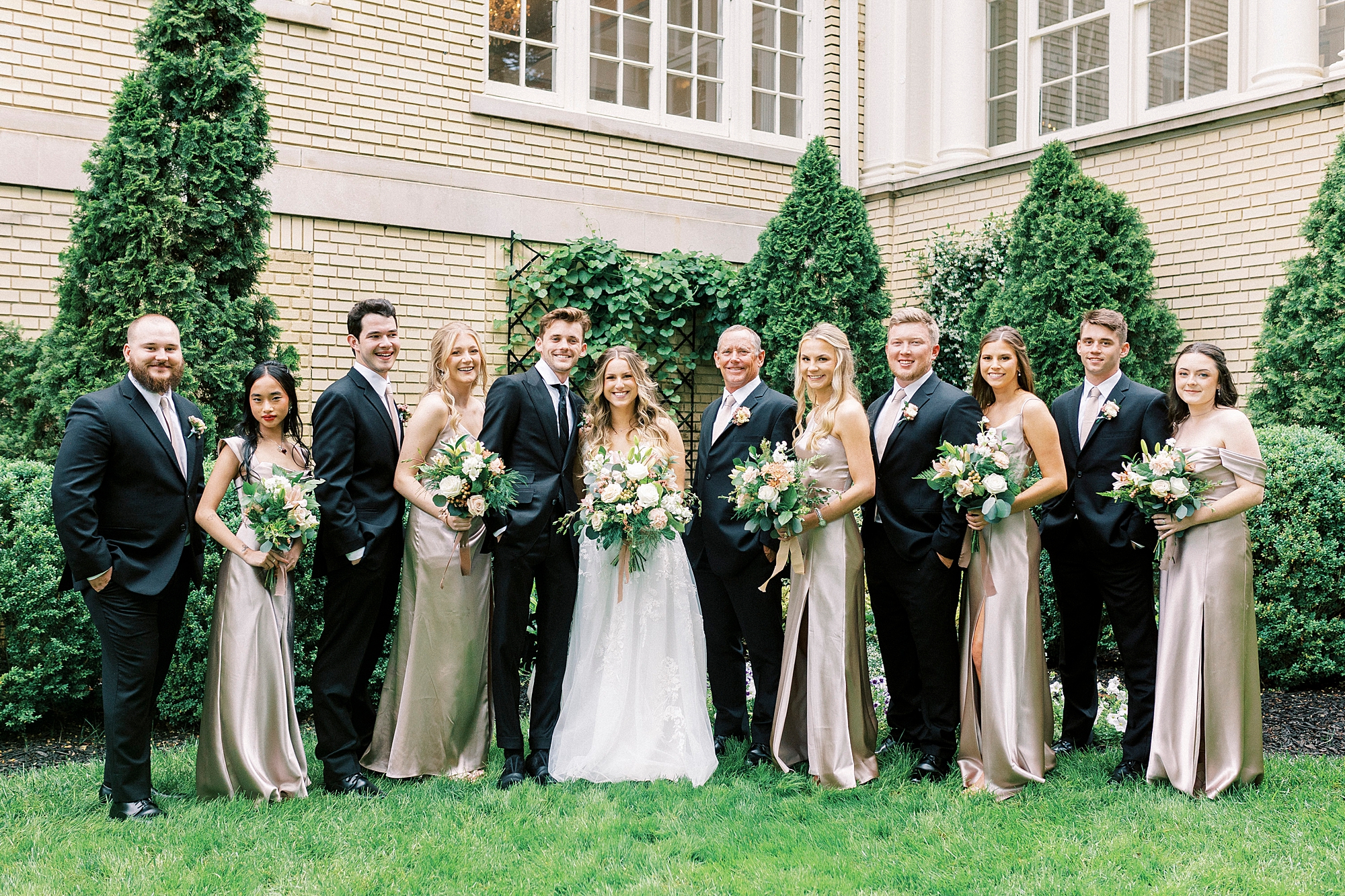 bride and groom stand with wedding party in garden at Separk Mansion