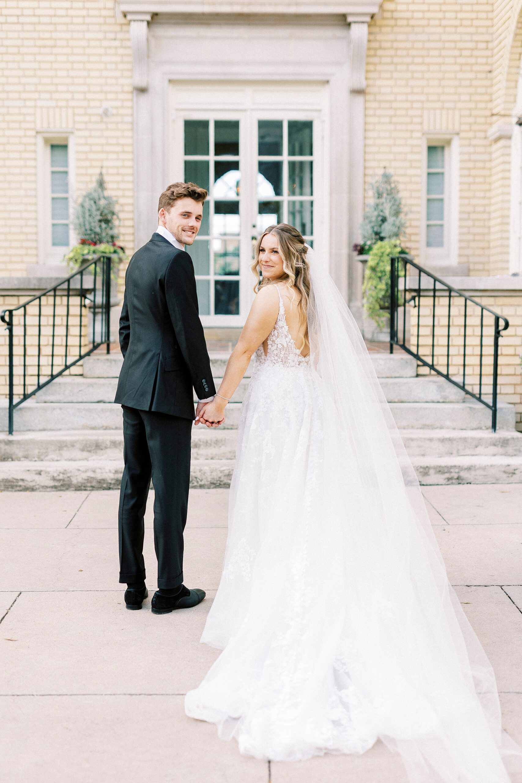 newlyweds hold hands turning looking over shoulder at Separk Mansion
