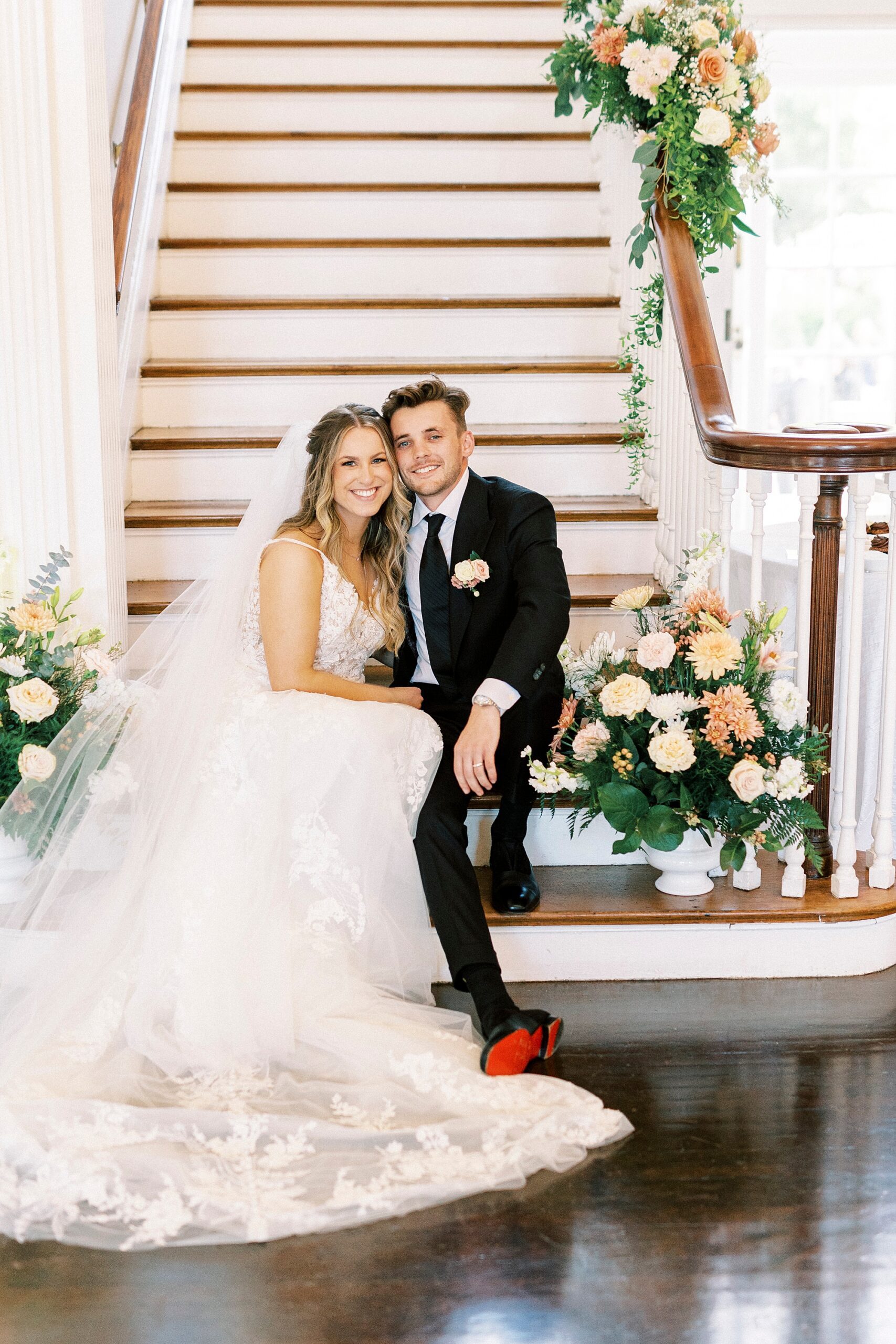 bride and groom sit on steps with flowers around them at Separk Mansion
