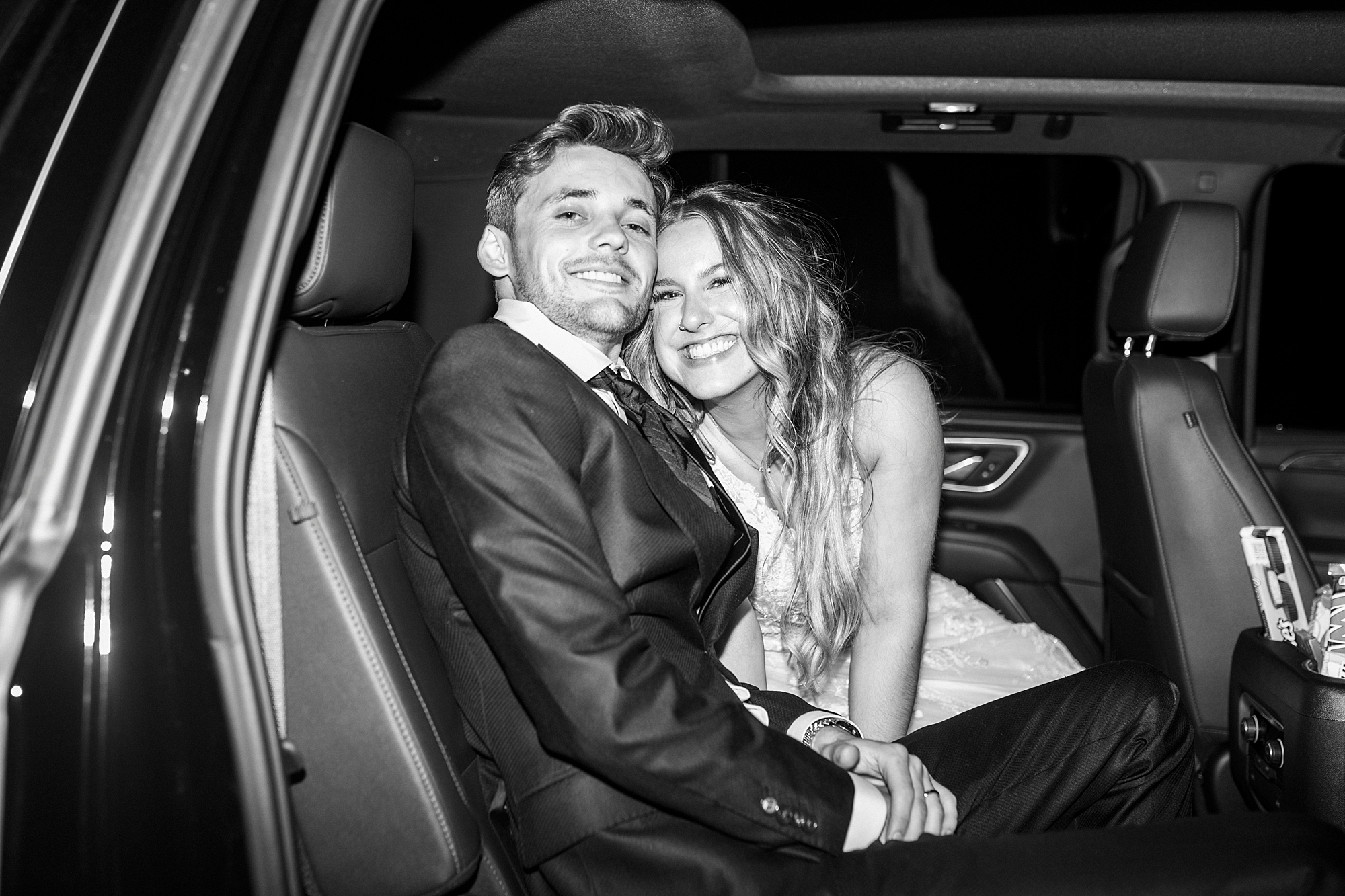 bride and groom hug sitting inside limo