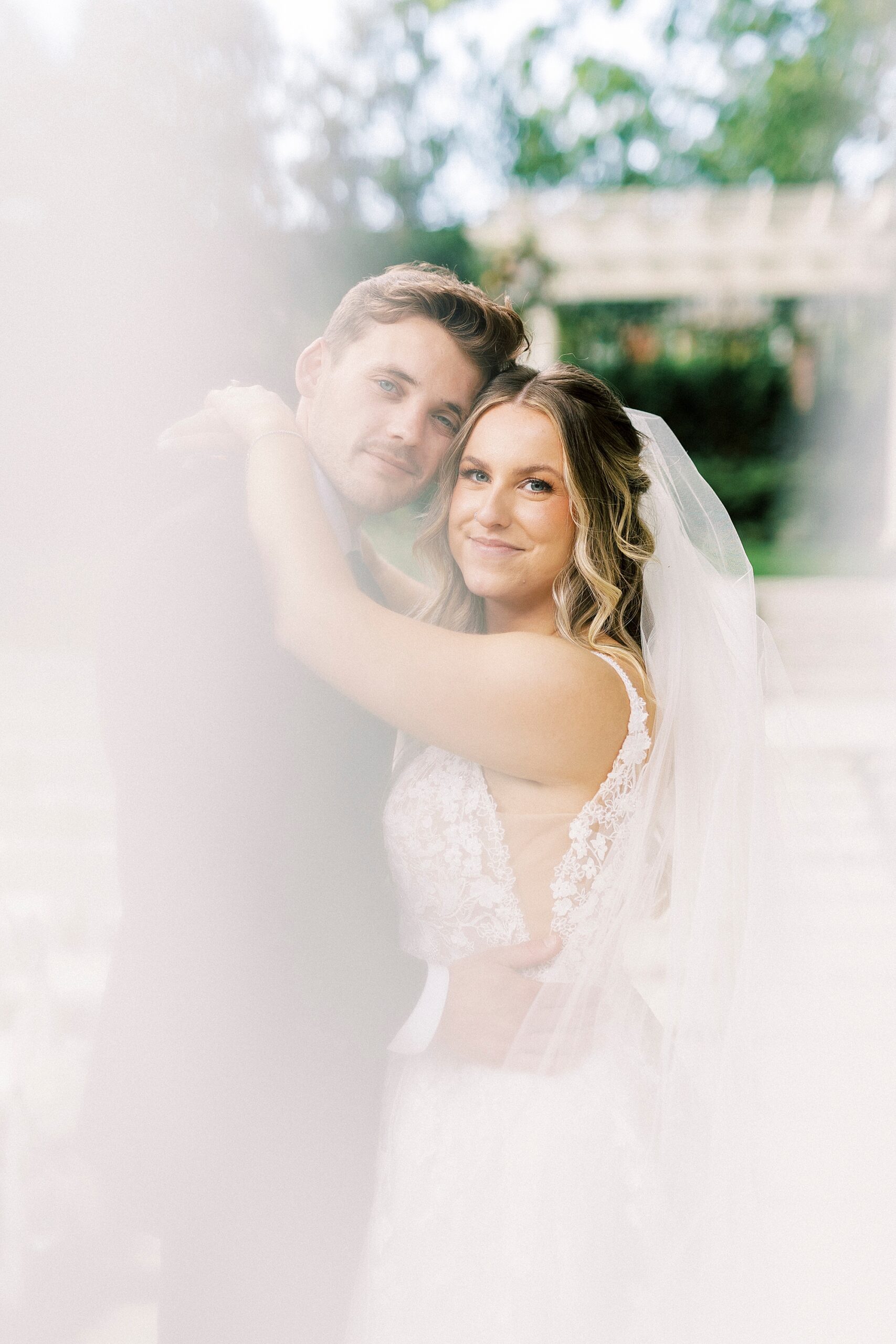bride and groom hug with photo obscured by veil 