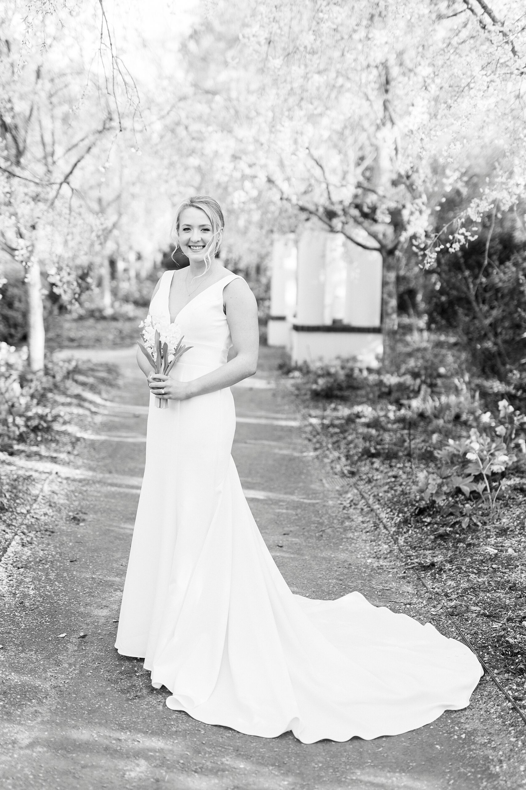 bride stands on walkway in Reynolda Gardens holding bouquet