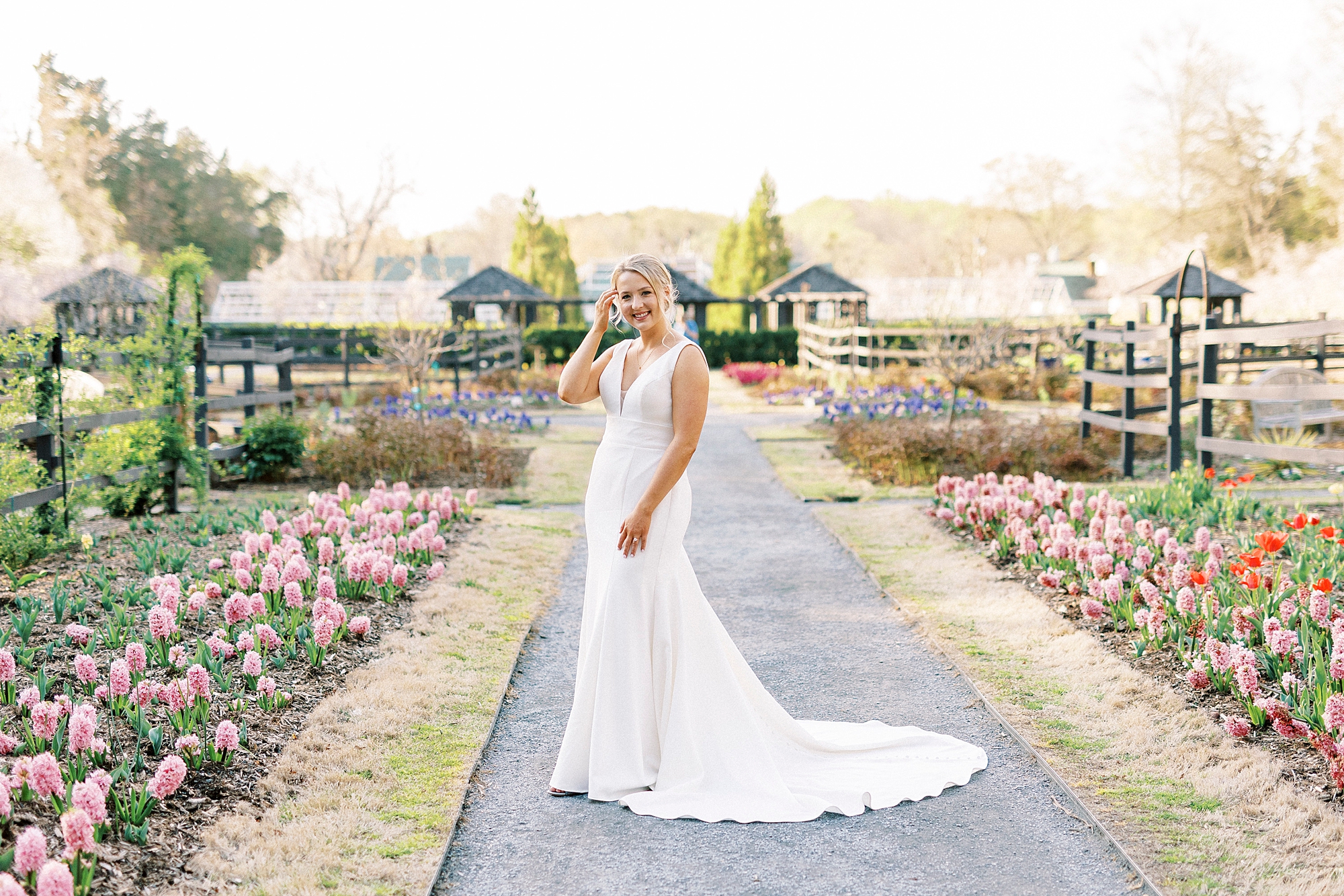 bride poses between rows of flowers at Reynolda Gardens in wedding gown
