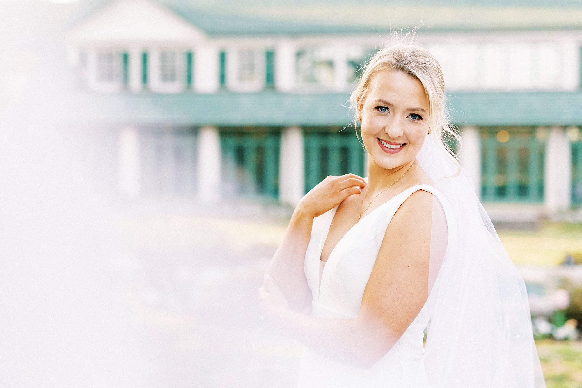 bride smiles with veil draped around her outside Reynolda Gardens home