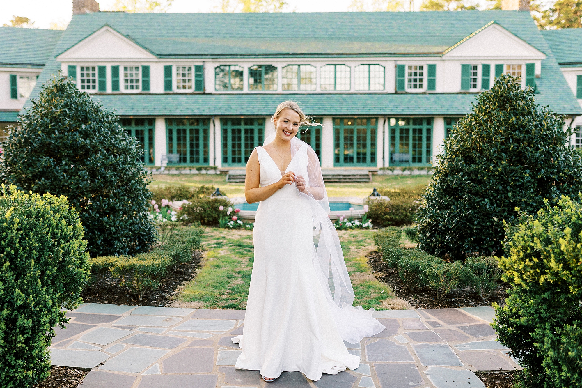 bride stands in front of white and green house of Reynolda Gardens