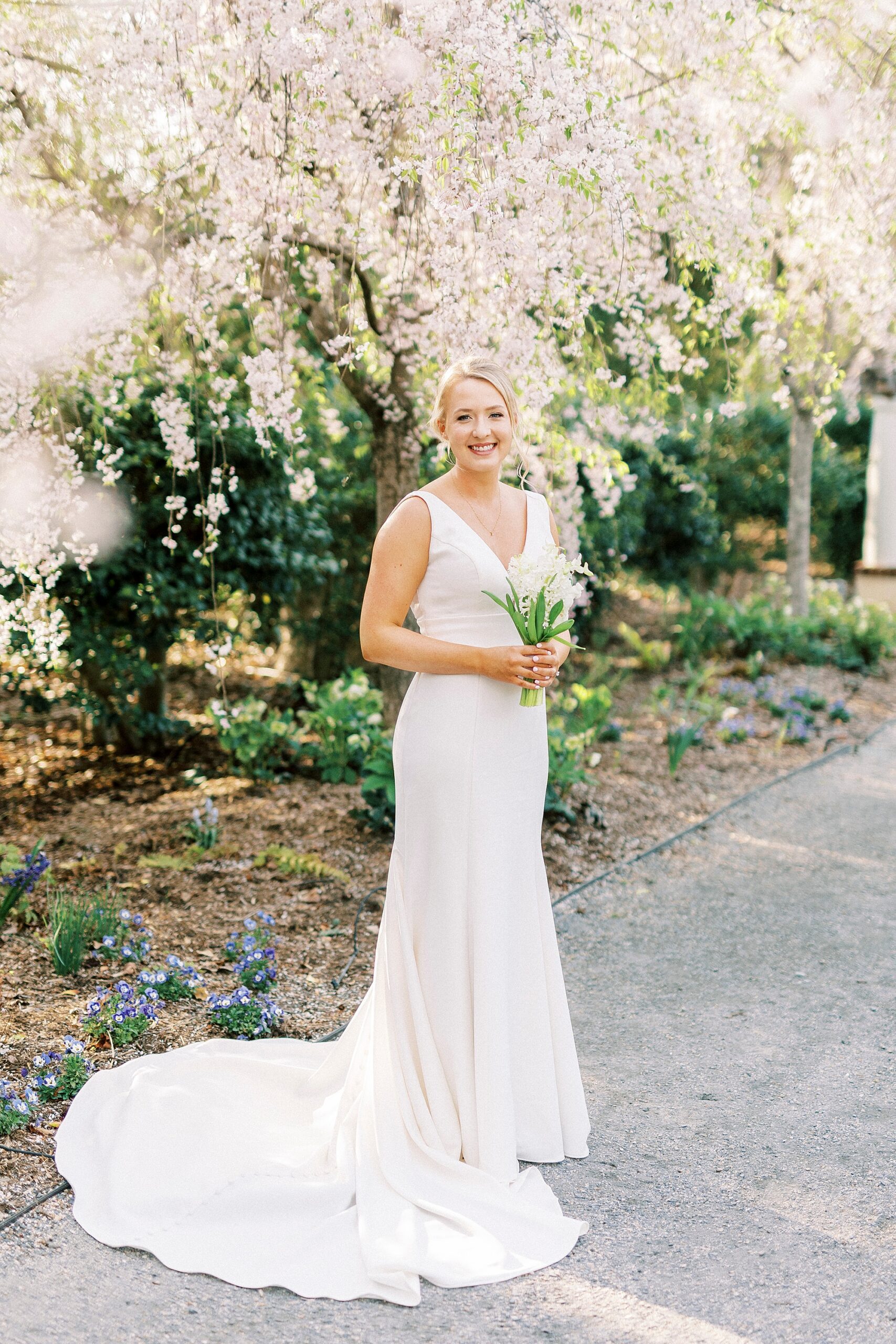 bride smiles holding bouquet of white hyacinths at Reynolda Gardens