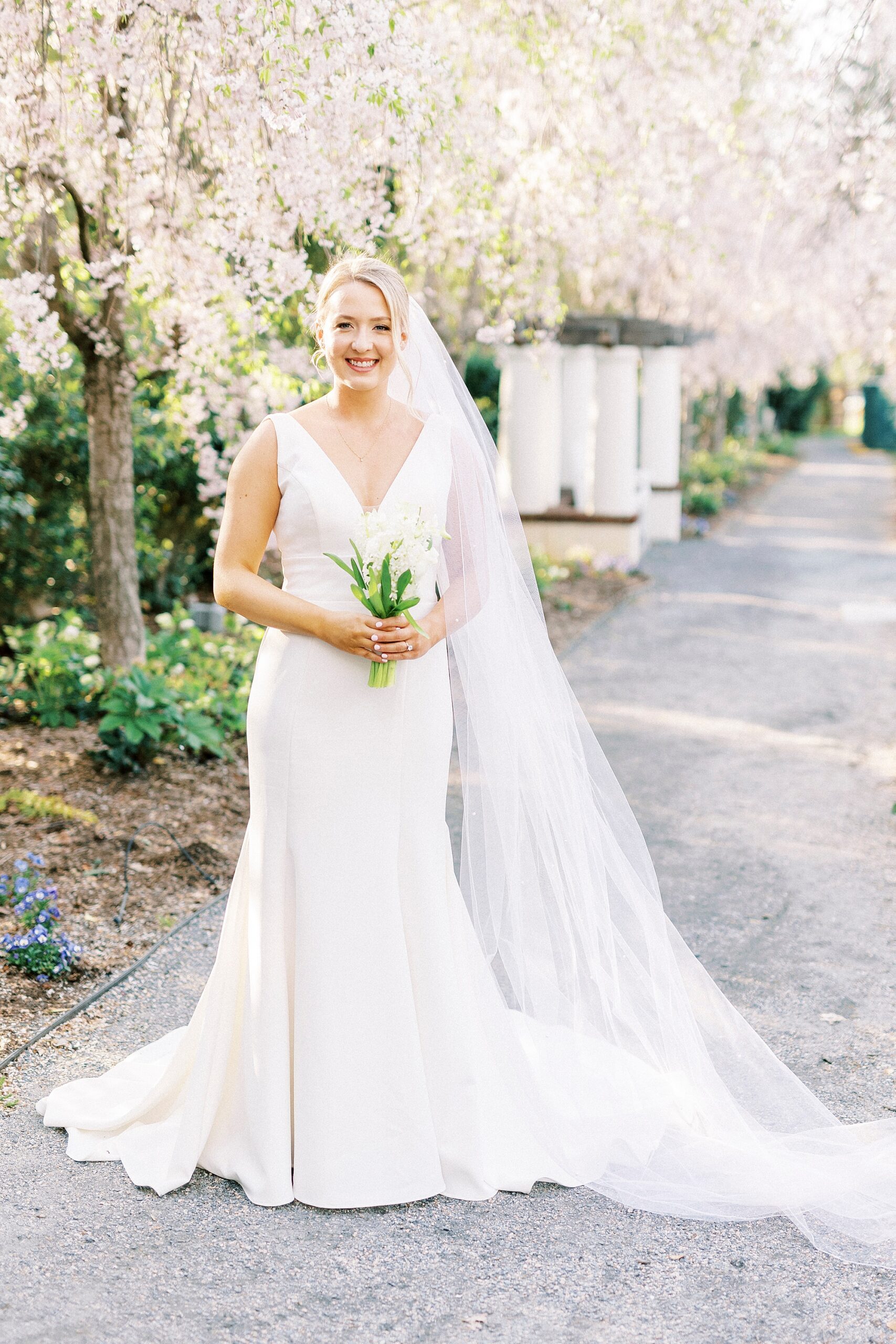 bride smiles with veil draped along her arm at Reynolda Gardens