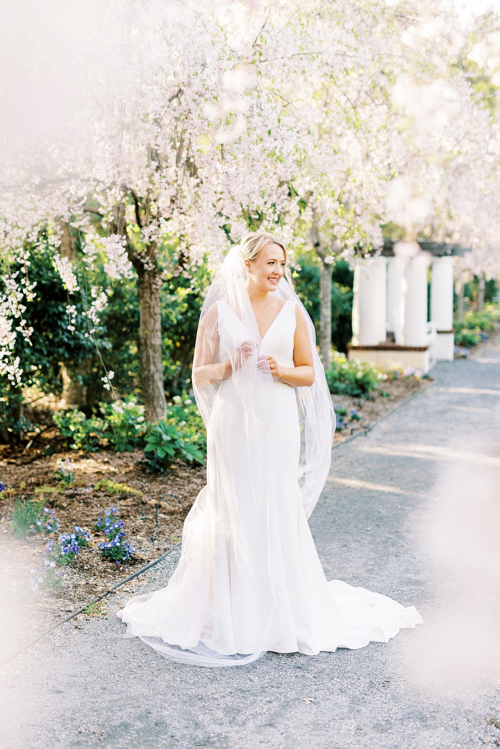 bride-to-be pulls veil around her shoulders on walkway at Reynolda Gardens